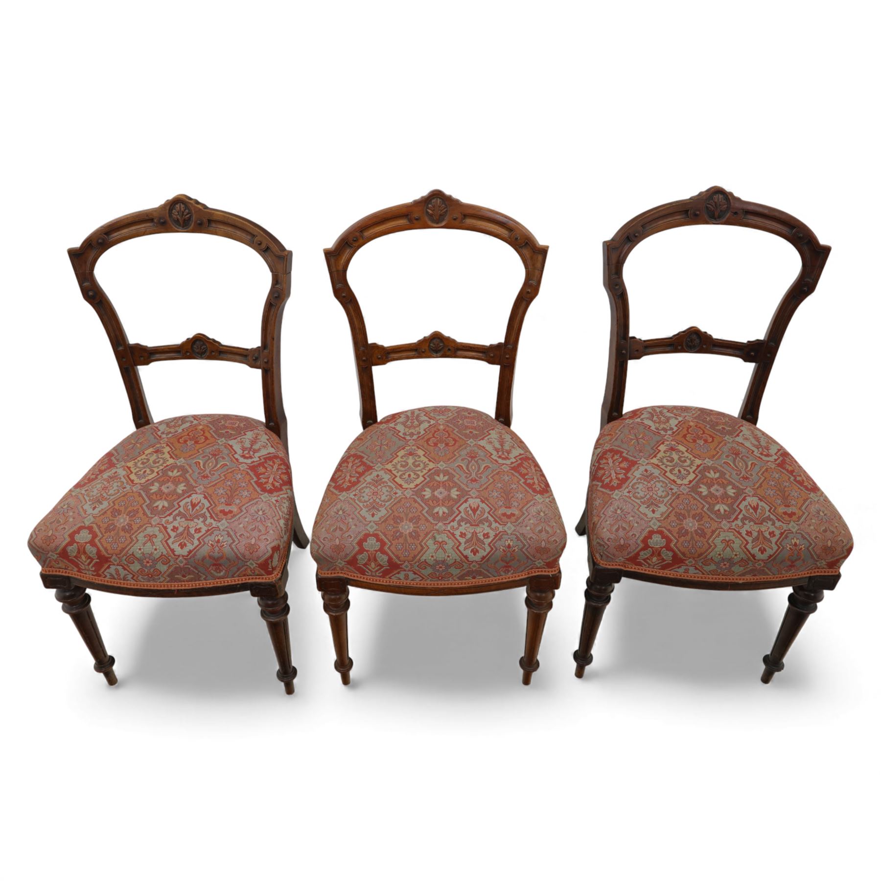 Set of six late Victorian mahogany dining chairs, the shaped top rails carved with anthemion motifs, above pierced splats, floral and geometric fabric seat, on turned and fluted front legs