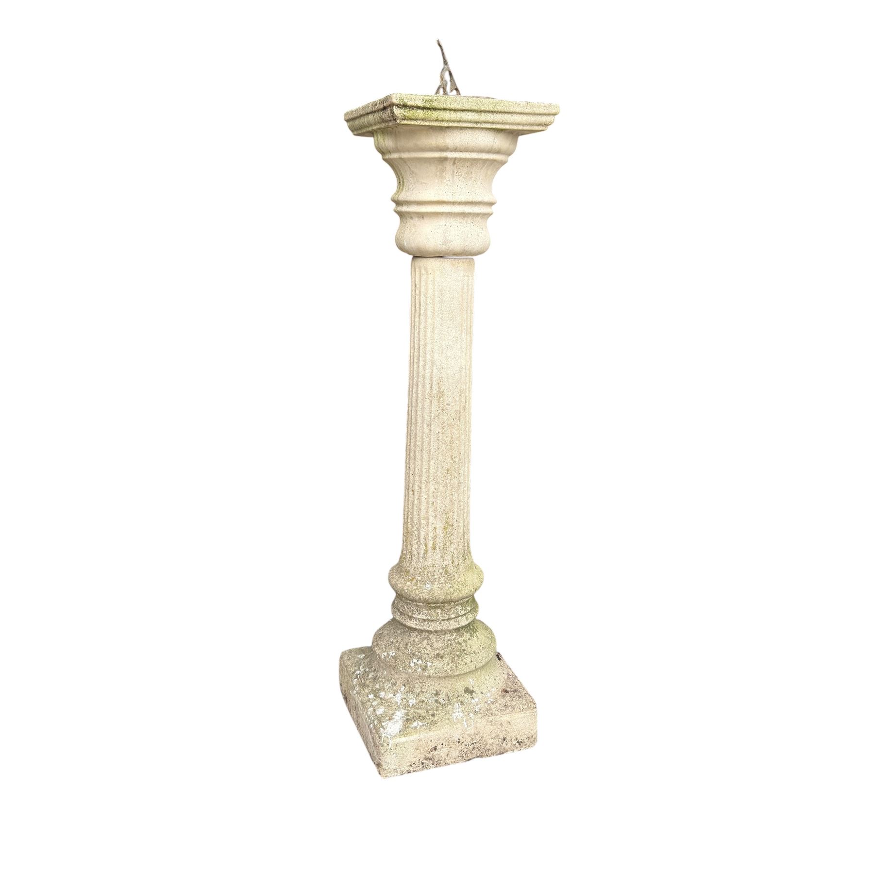 Weathered cast stone sundial on fluted pedestal
