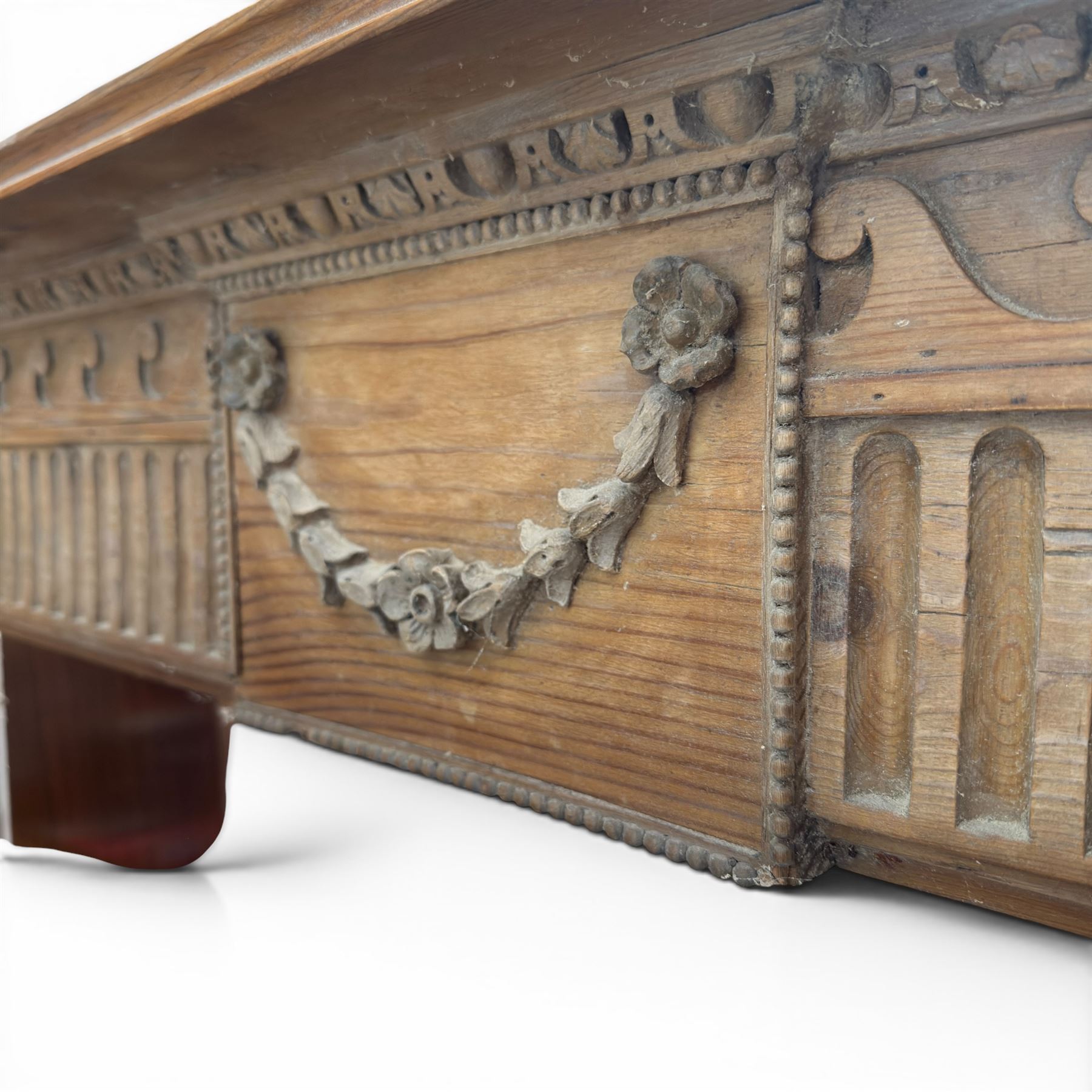 19th century Adams design pine fire surround, egg-and-dart carving over Vitruvian scrolls and fluted frieze, decorated with applied carved festoons and garlands, on fluted uprights