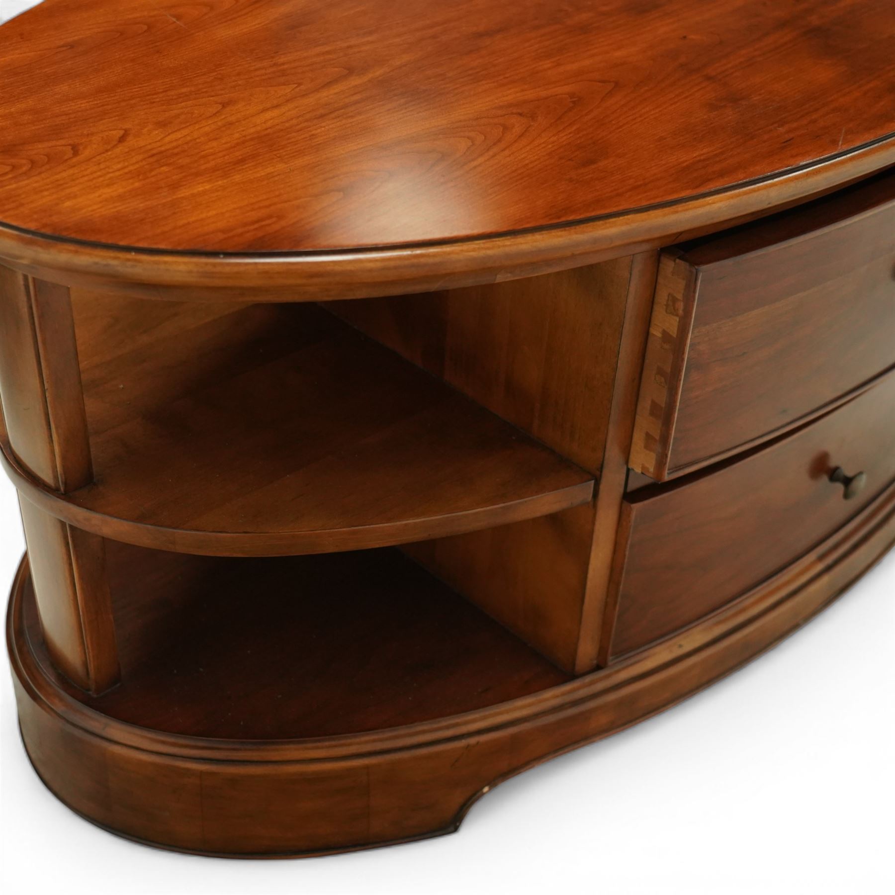 Willis & Gambier - oval coffee table, the moulded oval top above two central frieze drawers with handles either side, flanked by open shelves, raised on a shaped plinth base