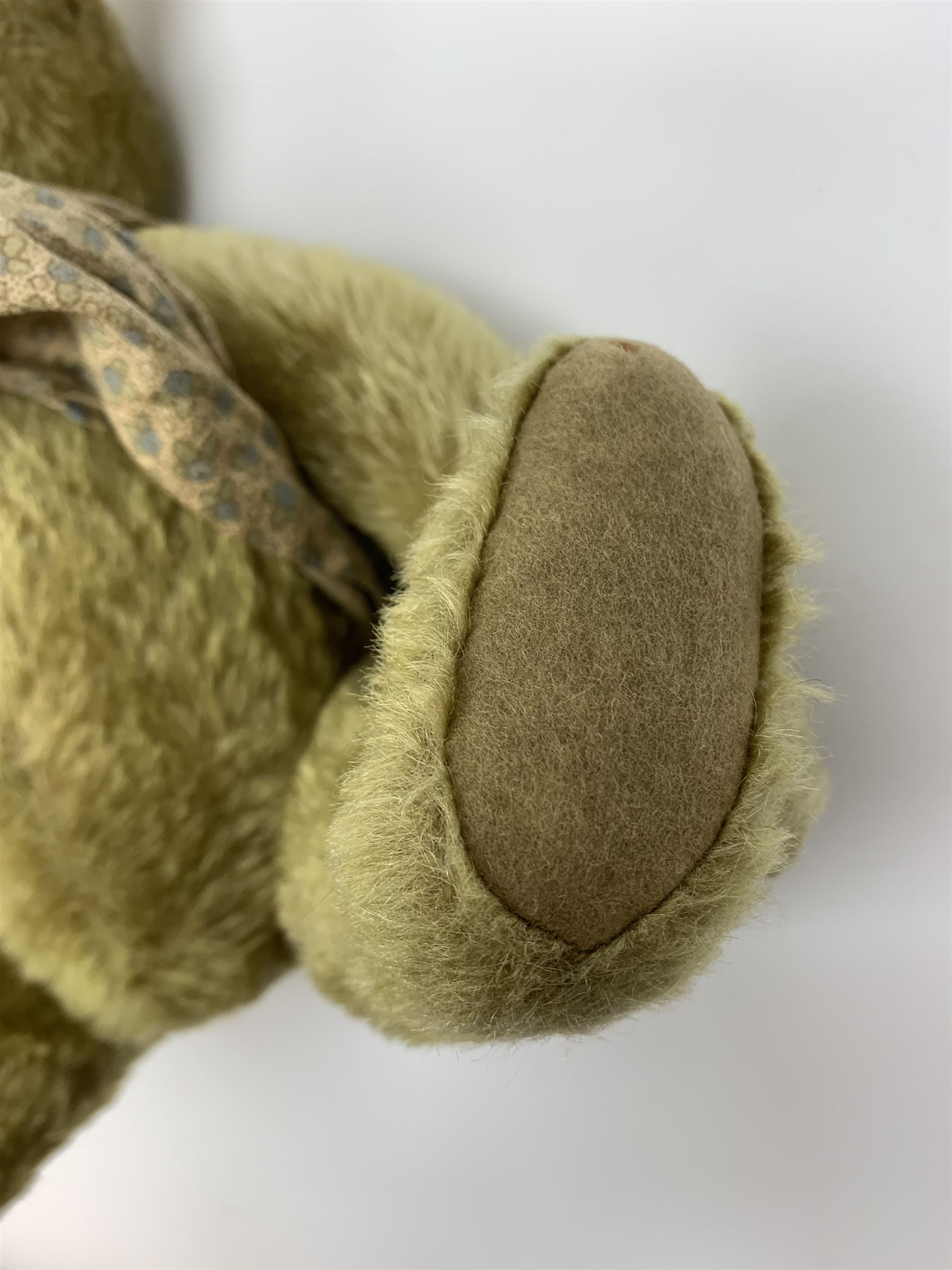 Early 20th century German Steiff teddy bear c1910 with wood wool filled humped back mohair body, swivel jointed head with black boot button eyes and horizontally stitched black nose and mouth, FF metal button to left ear, jointed elongated limbs with felt paw pads and black stitched claws H13