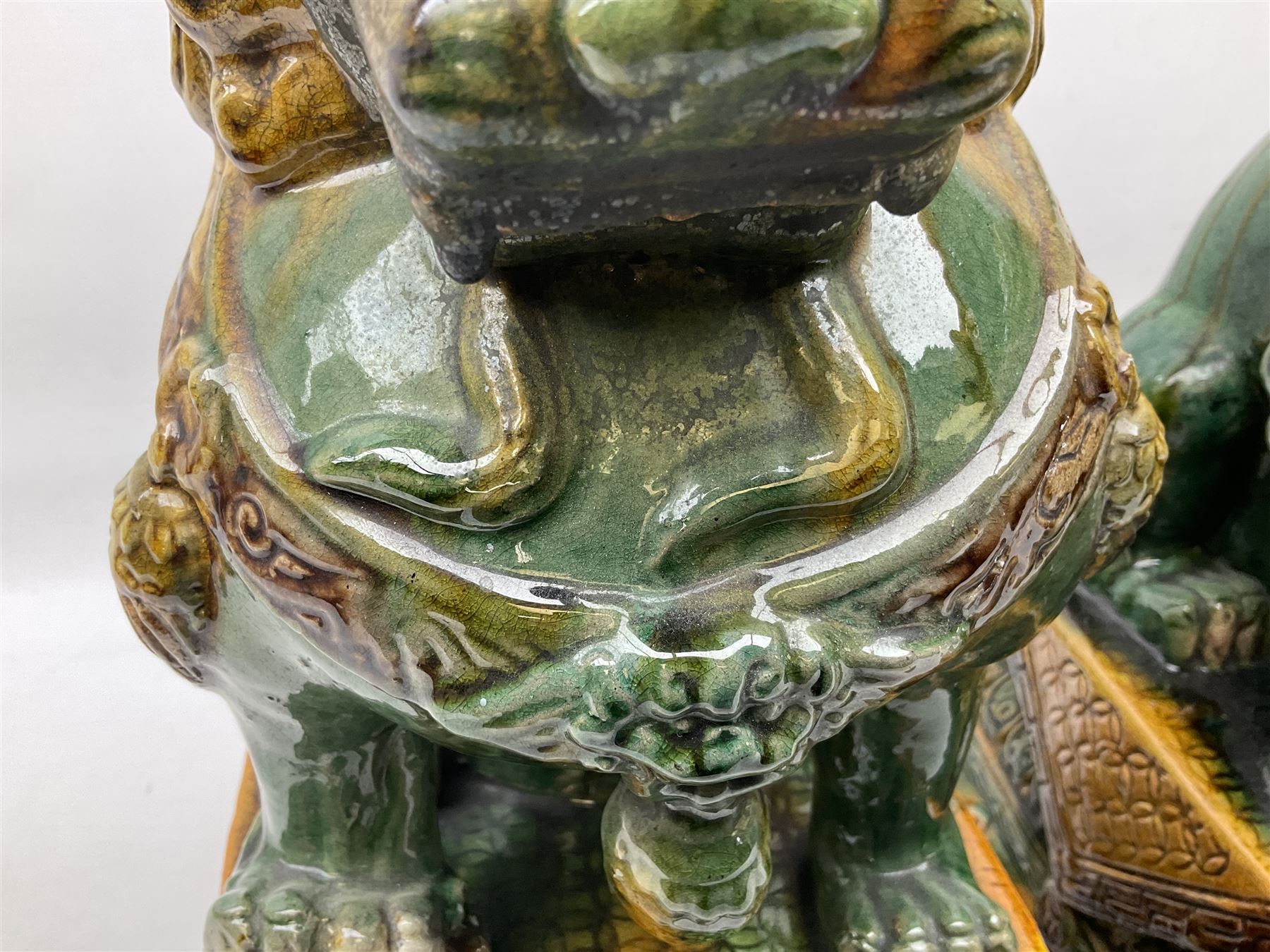 Pair of Chinese Temple Lions or Dogs of Foo, modelled in seated post, one with one front paw resting upon a ball, the other upon a cub, each upon stylised plinth base, H44cm