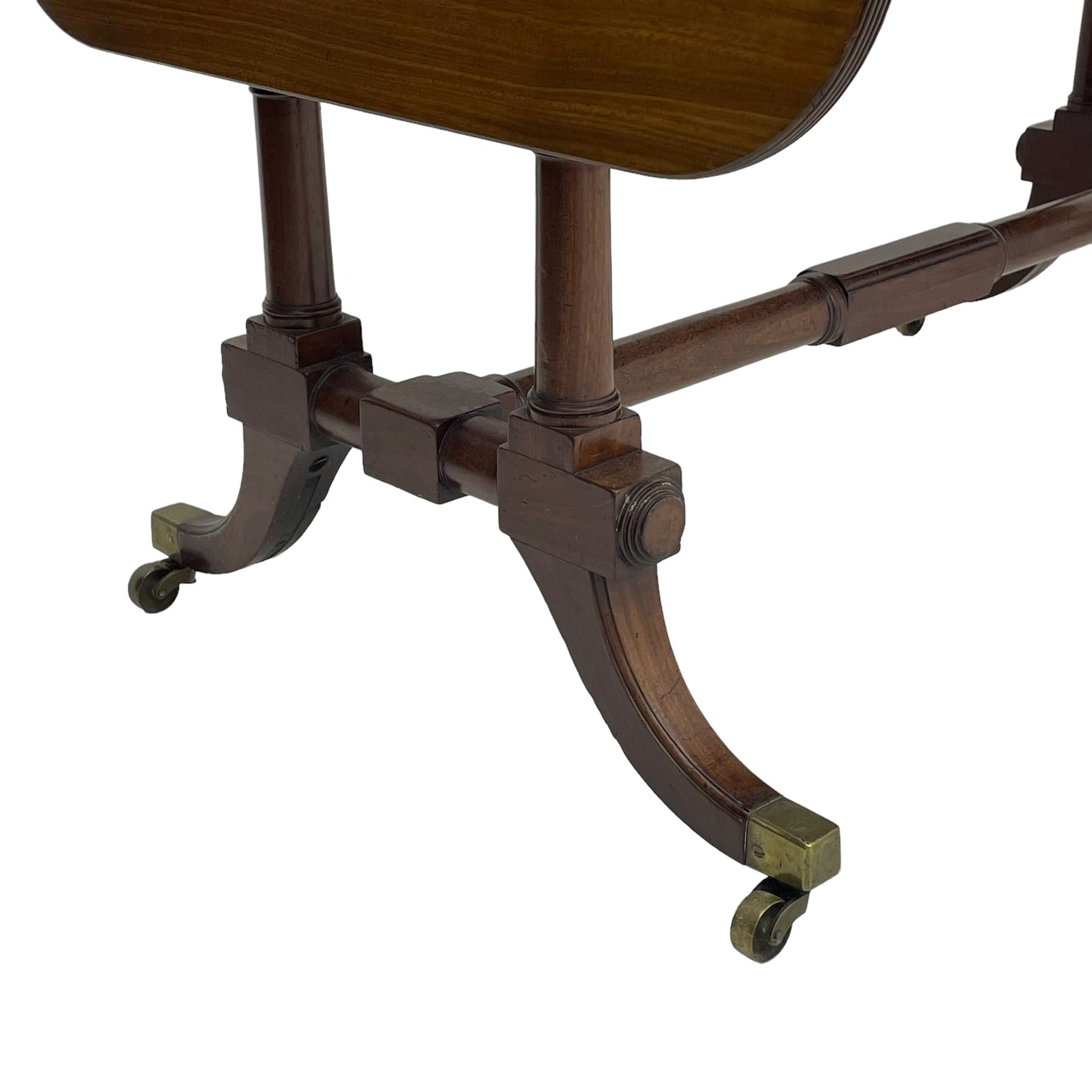 George III mahogany sofa table, rectangular drop-leaf top with reed moulded edge and rounded corners, fitted with two frieze drawers and two opposing false drawers, quadruple collar turned pillar supports on turned and block platforms, splayed and moulded supports with brass cups and castors 