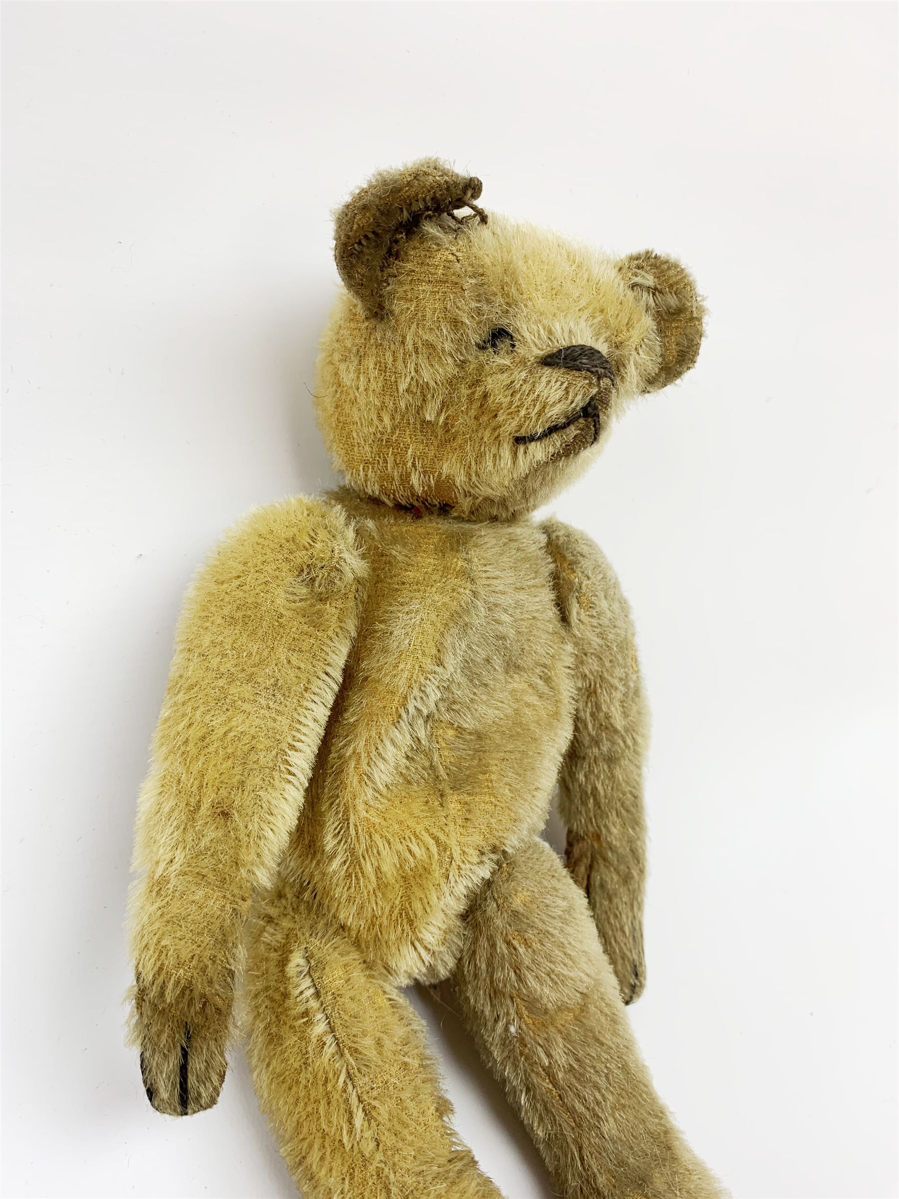 Early 20th century American mohair teddy bear c1920 with wood wool filled body humped back body with jointed limbs, black boot button eyes and horizontal stitched nose and mouth H12