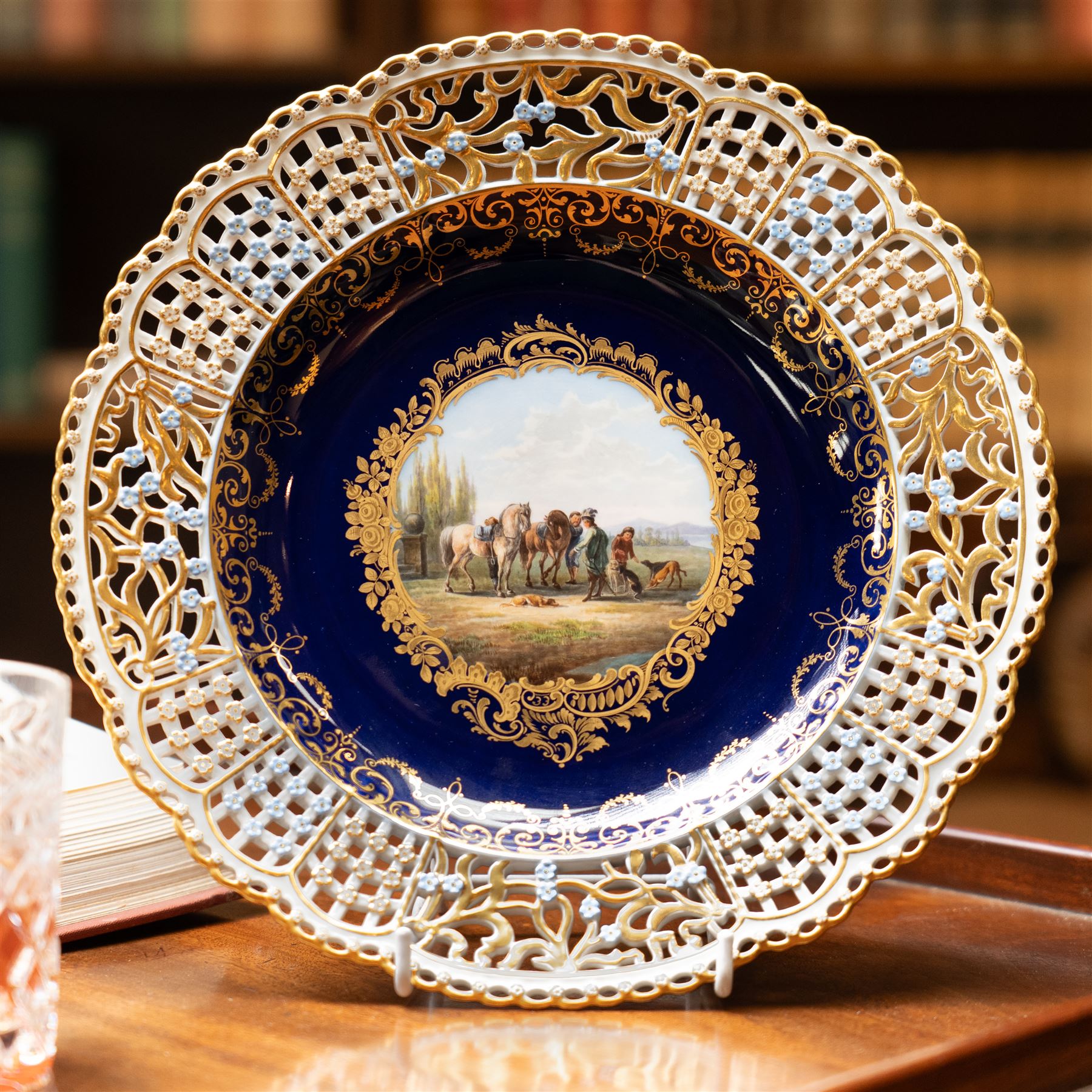19th century Meissen cabinet plate, the reticulated border modelled with trellis panels and forget-me-nots,  the cobalt blue well with gilt bordered central reserve painted with a scene of a hunting party resting after Philips Wouwerman (Dutch 1619-1668), underglaze blue crossed swords and indistinct impressed numbers verso, D26cm