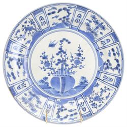 Two Japanese Edo period Ko Imari blue and white porcelain chargers, each decorated in the Kraak style with urns issuing peonies, pine and prunus, within panelled borders containing flowers, tress and precious objects, each approximately D 31.5cm