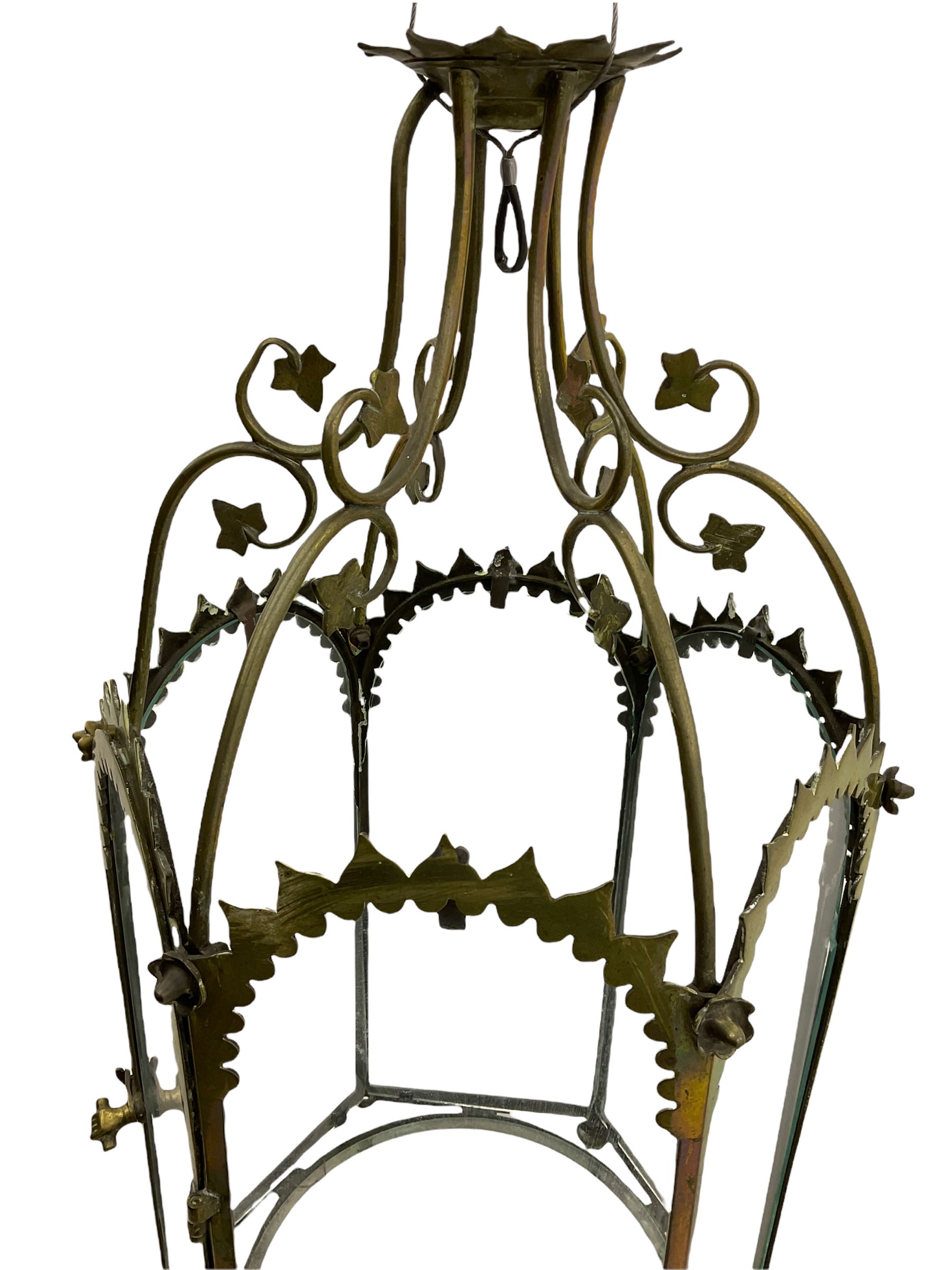 19th century brass and clear glass hexagonal hall lantern, with scrolling wire work open domed top over six arched panels, including a hinged door, the base enclosed with a circular glass panel on turned feet, H64cm