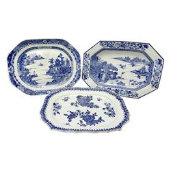 Two late 18th/early 19th century Chinese export blue and white platters and dish, each of rectangular form with canted or shaped corners, two examples decorated with waterside landscapes, the third with blossoming flowers, largest example W40cm