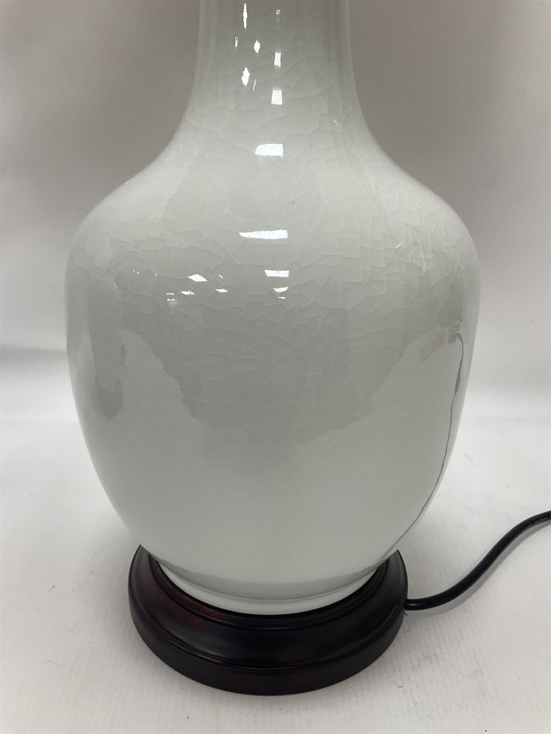 Pair of Chinese ivory crackle glazed table lamps, each of bottle form, raised upon circular hardwood base, excluding fittings H43cm