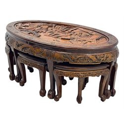 Early 20th century Chinese hardwood nesting coffee table, oval top carved with figures and traditional pagoda scenes with carved frieze, complete with six inset stools or side tables, raised on tapering supports with paw feet