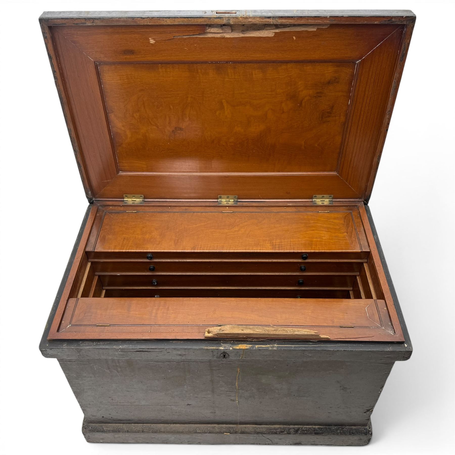 20th century black painted camphorwood lined tool chest, rectangular hinged lid over moulded edge, black painted exterior with iron straps and carry handles, the interior fitted with sliding lidded trays and drawers with turned handles, containing an assortment of hand tools