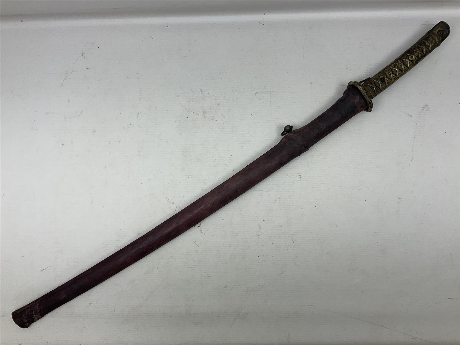 Copy of a WWII Japanese NCO sword, the 65cm slightly curving blade stamped with pseudo Japanese characters and cast brass simulated cord bound grip; in officer's leather bound field scabbard L97cm overall