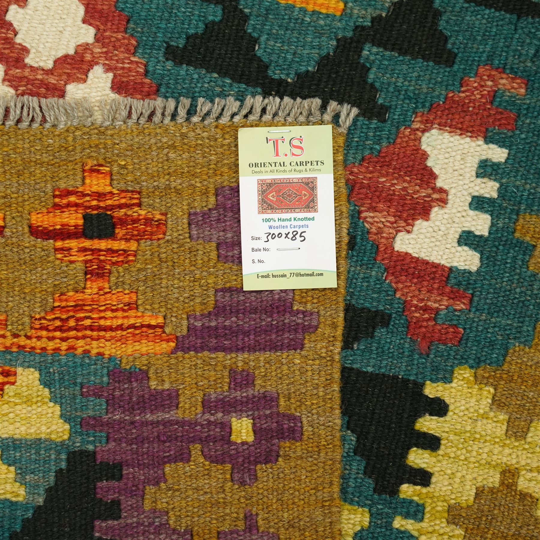 Maiman kilim, woven with an arrangement of multicoloured diamonds on a dark ground with contrasting ivory and ochre highlights, enclosed by a broad border featuring alternating geometric devices in green, mustard, red and blue