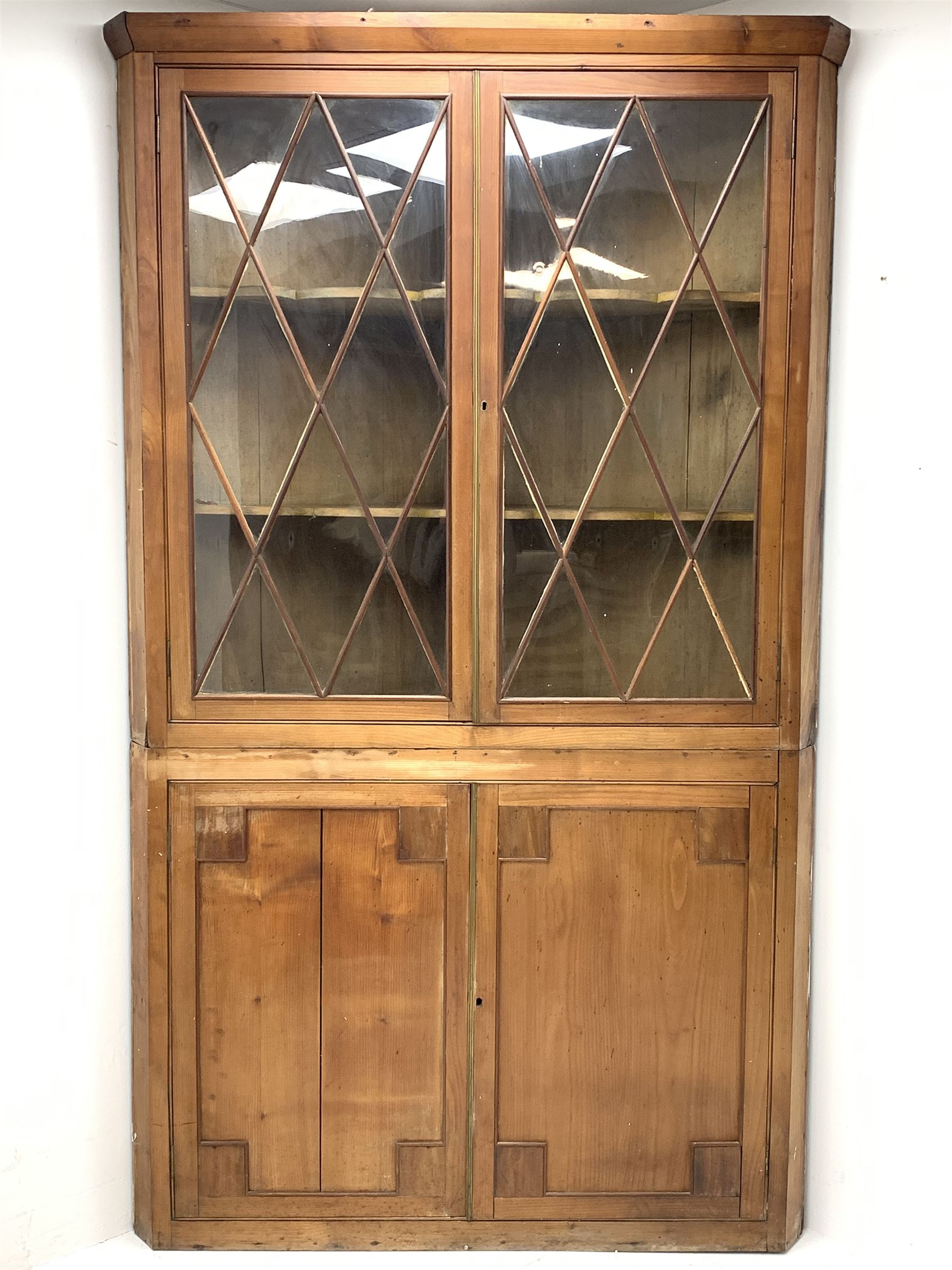 Large late 19th century sycamore corner cabinet, the top section with two astragal glazed doors enclosing two shaped shelves, the lower section enclosed by two panelled doors with square spandrels, W128cm, H215cm