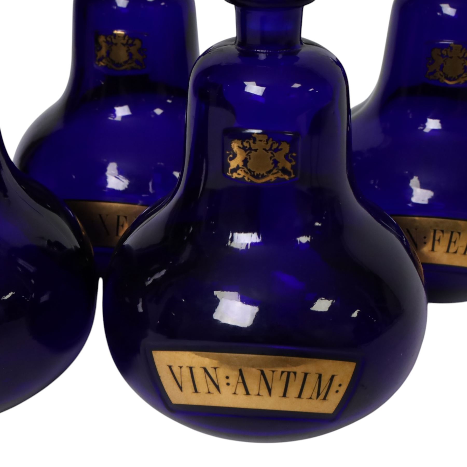 Set of four 20th century Royal Pharmaceutical Society blue glass bottles, of bellied form with clear cut glass spire stopper, each body bearing gilt label in Latin: VIN:ACET:, VIN:ANTIM:, VIN:XERIC:, and VIN:FERR:, and gilt Royal Pharmaceutical Society crest to neck, H25cm

Provenance: From the collection of the family of Peter Green, a practising pharmacist whose career spanned the mid to late 20th century. During his professional life he managed pharmacies in Yeovil, Somerset, and later Selles Chemist in Filey, North Yorkshire, before purchasing and running his own business, Peter Green Pharmacy, located in the Market Place, Malton. The bottles were displayed as part of the traditional shop fittings in both the Filey and Malton pharmacies and were retained as part of his collection.