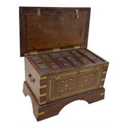 Zanzibar chest, early 20th century, of hardwood construction with brass inlaid foliate and geometric decoration to the lid, fitted interior of multiple carved compartments, with brass strapwork, side handles, and shaped bracket feet