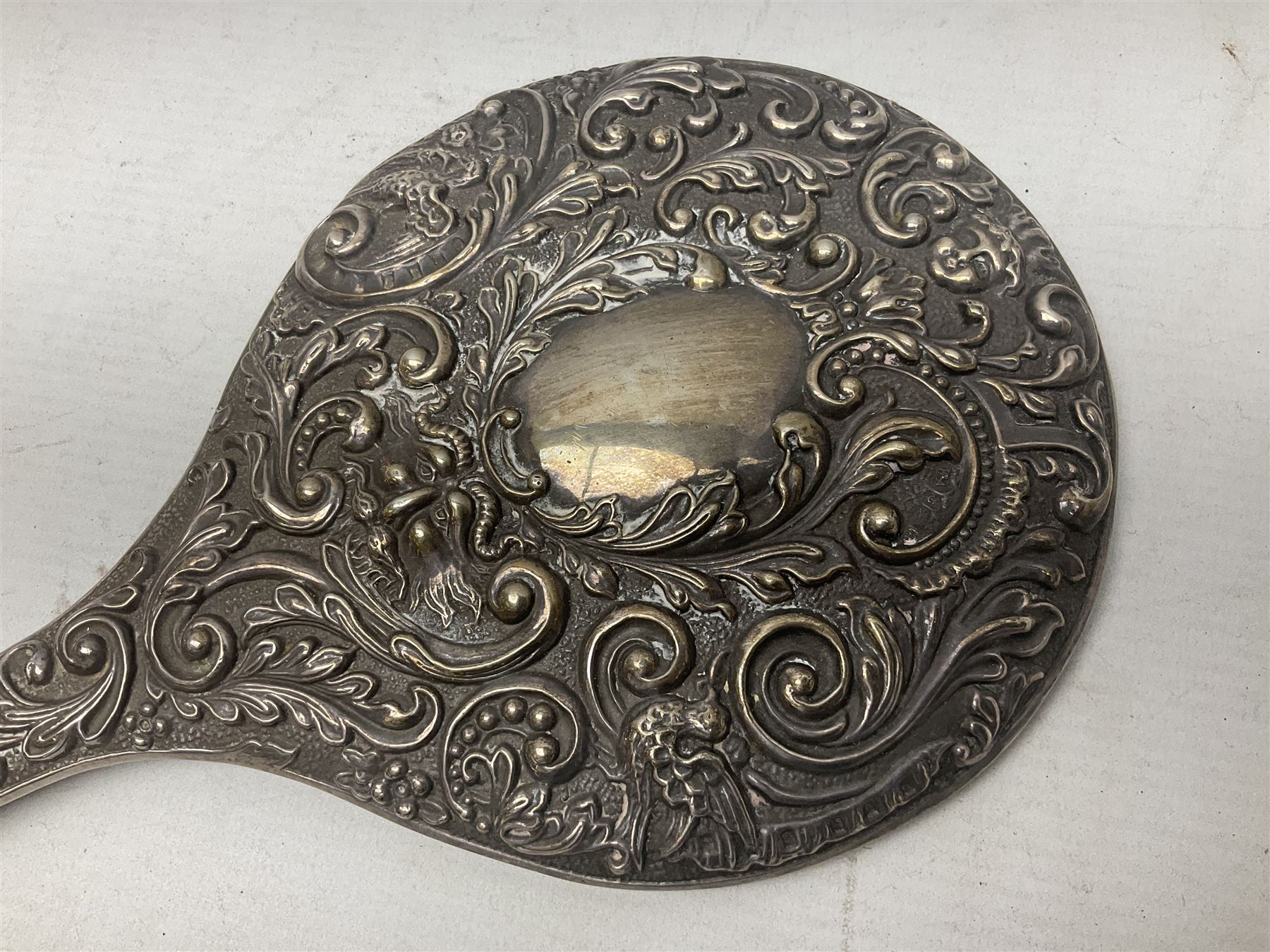 Silver mounted dressing table mirror, embossed with birds, masks, and foliate and C scrolls, hallmarked Birmingham, and fruit knife with mother of pearl handle and silver blade, (2)