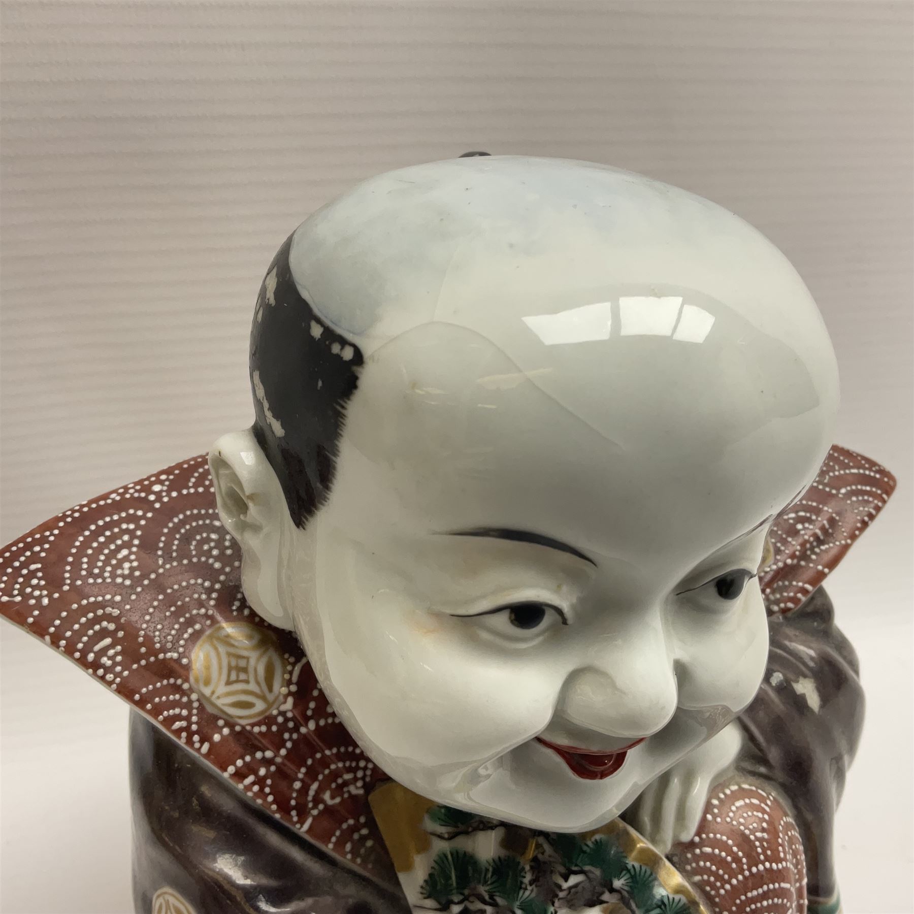 Japanese Fukusuke good fortune figure, modelled as a kneeling male figure holding a fan, dressed in traditional Samurai robes, H15.5cm