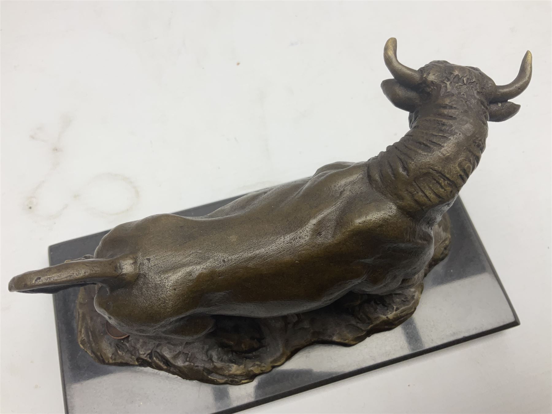 Bronze figure, modelled as a prancing bull, upon a naturalistic base signed Mils and with foundry mark, raised upon a rectangular marble base, overall H14cm