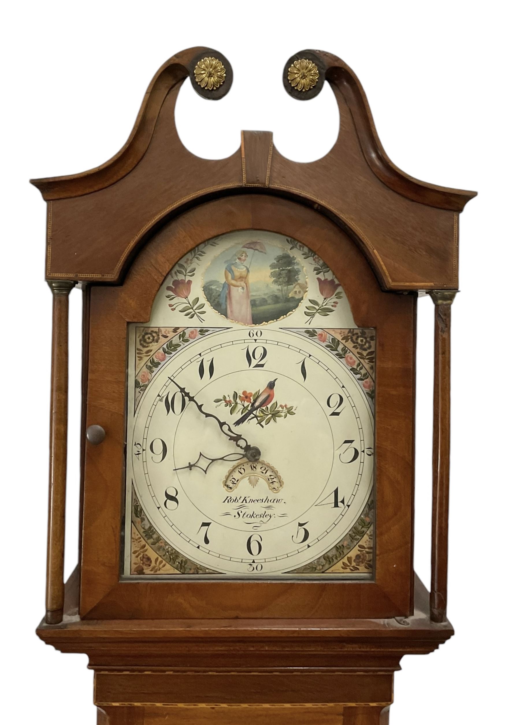 Robert Kneeshaw of Stokesley - 19th century 30 hour mahogany cased longcase clock c1820. with a swans necked pediment and brass paterie, break arch hood door with plain pilasters, inlaid trunk with canted corners, inlay and a wavy topped door, on a rectangular plinth with a shaped base, painted dial with floral spandrels and a depiction of a lady walking in the countryside, with Arabic numerals, non-matching steel hands, calendar aperture and an image of a bird of paradise to the centre, chain driven countwheel striking movement, with weight and pendulum.  