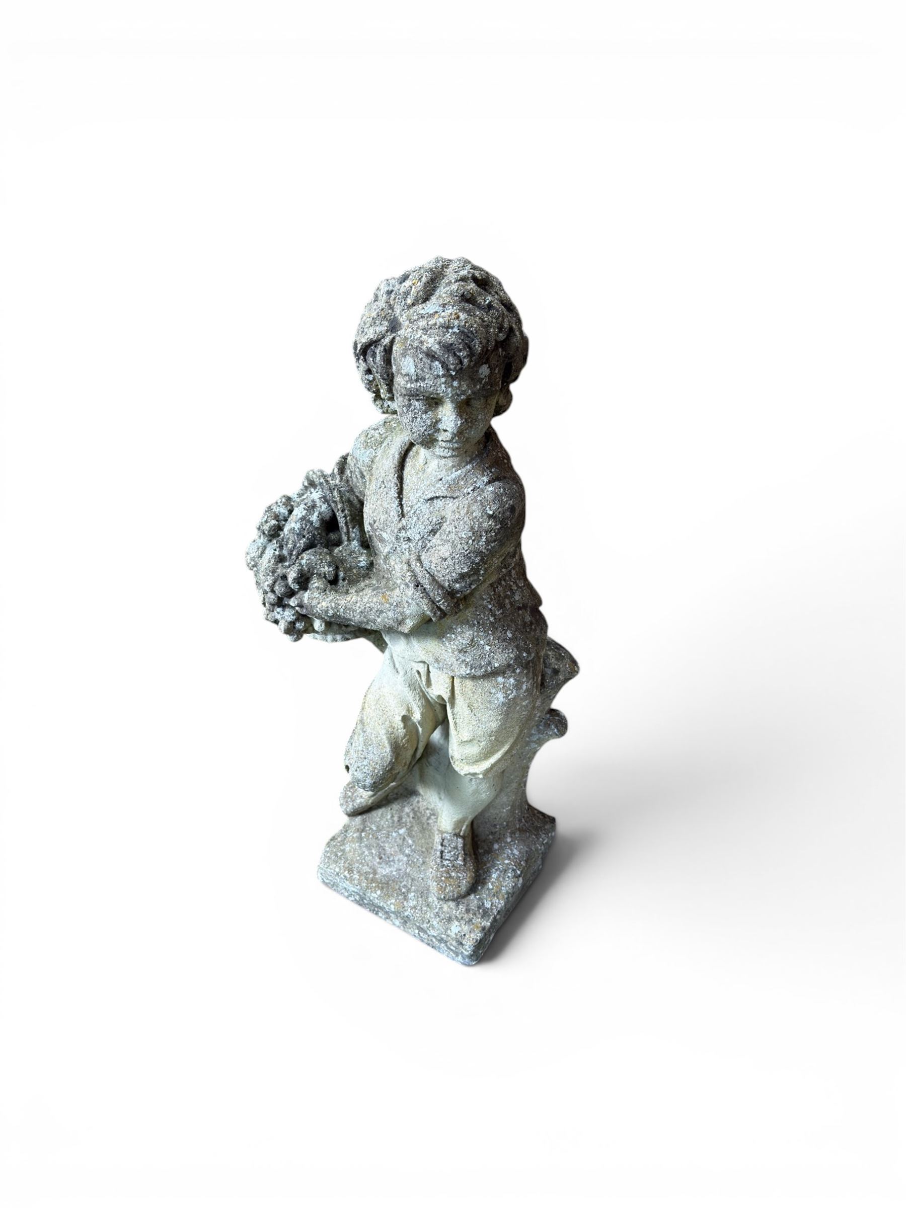 Weathered cast stone garden figure depicting a child holding a fruit basket