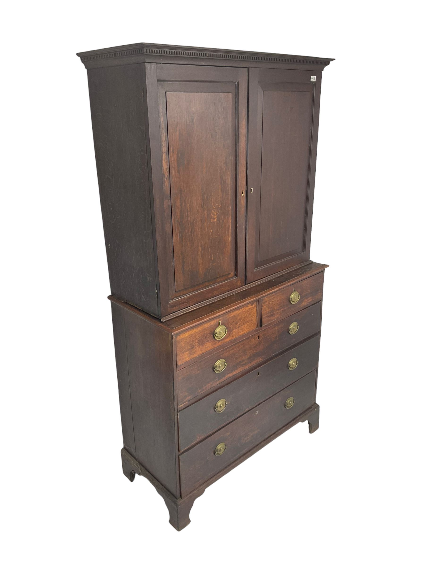 George III oak linen press, projecting cornice with dentil moulding over two panelled doors enclosing two adjustable shelves, fitted with two short over three long drawers, raised on bracket feet