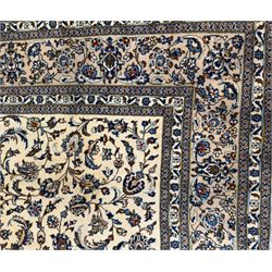 Central Persian Kashan hand-knotted carpet, ivory field with an all-over design of scrolling vines, lotus palmettes, and rosettes in shades of blue and brown within a blue ground border of palmettes and arabesques between multiple guard stripes, 
348 cm x 246cm