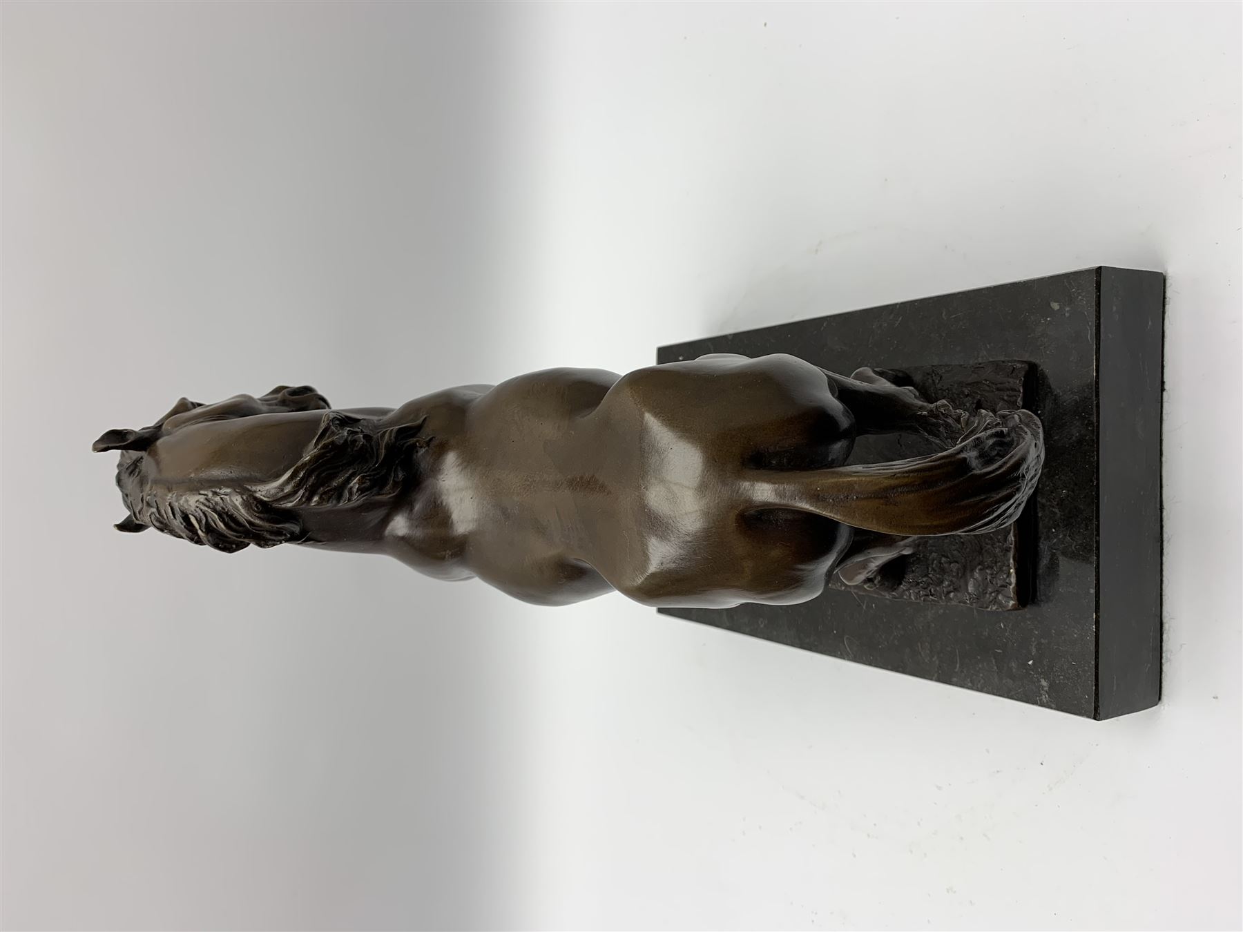 Bronze figure modelled as a prancing horse, upon a naturalistically modelled rectangular base, and black marble plinth, H34.5cm, L31cm