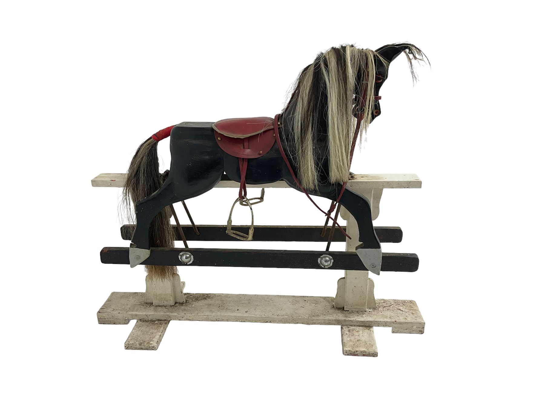 20th century black painted rocking horse on white painted trestle base, fitted with saddle and stirrups 