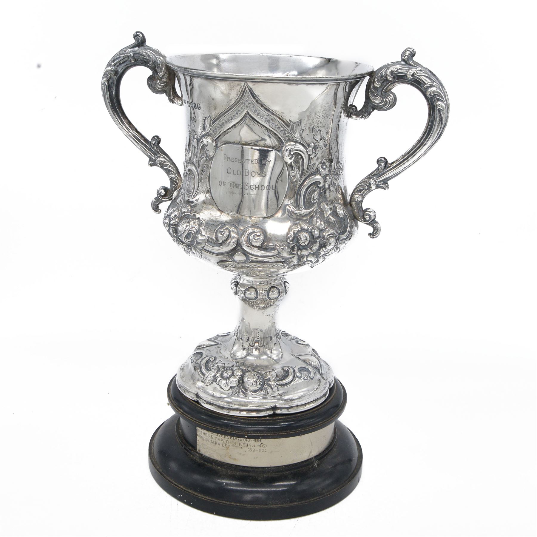 Victorian silver twin handled trophy, the bowl embossed with floral and scrolling decoration, with presentation engraving to body and twin acanthus capped C scroll handles, upon a lobed foot, hallmarked London 1866, maker's mark AM probably for Alexander Macrae, upon an ebonised wooden plinth, trophy only H25.5cm