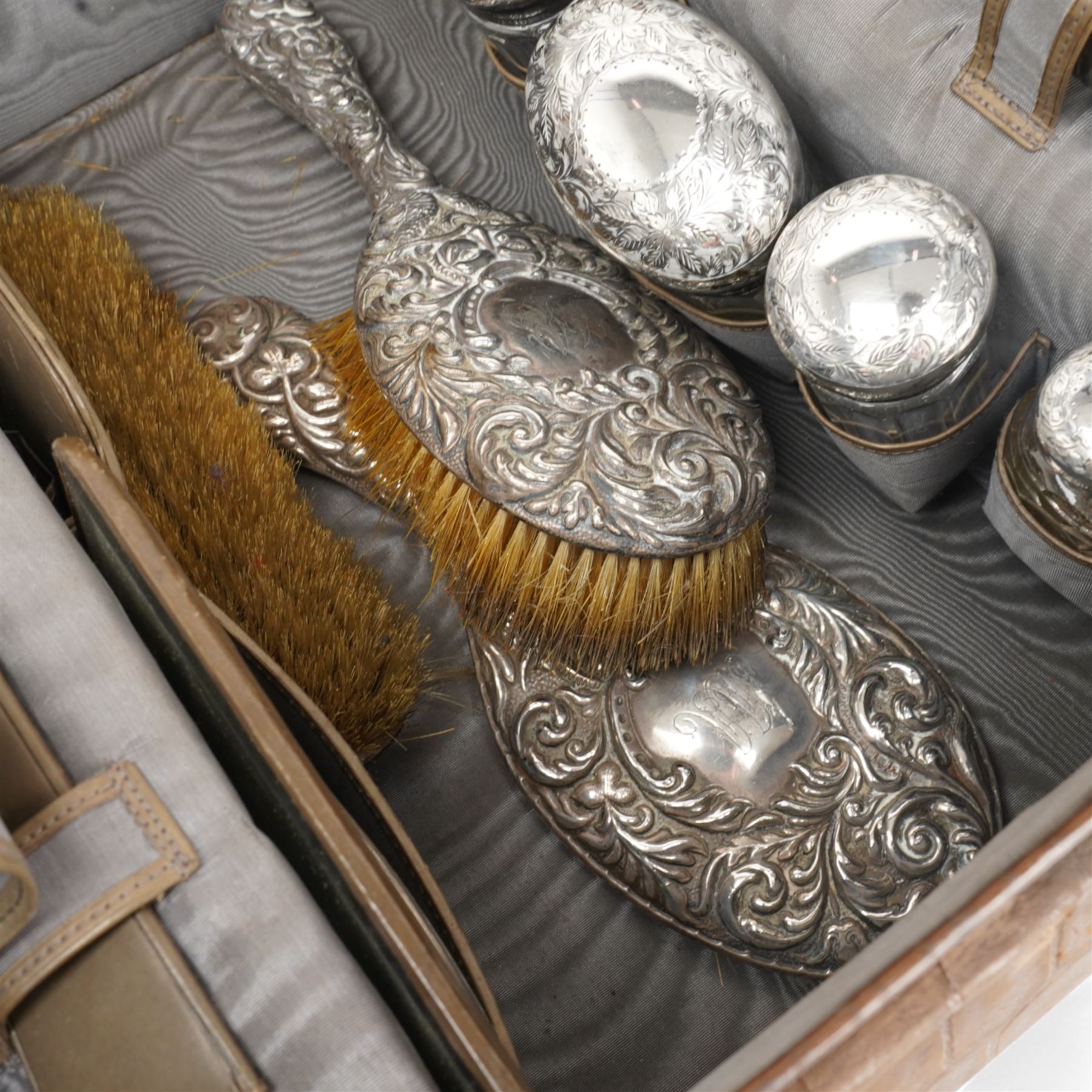 Ladies Edwardian crocodile travelling toilet case with watered silk interior containing six silver mounted glass jars Birmingham 1909 Maker Neal Bros. and a three piece dressing table set Sheffield 1898 W35cm