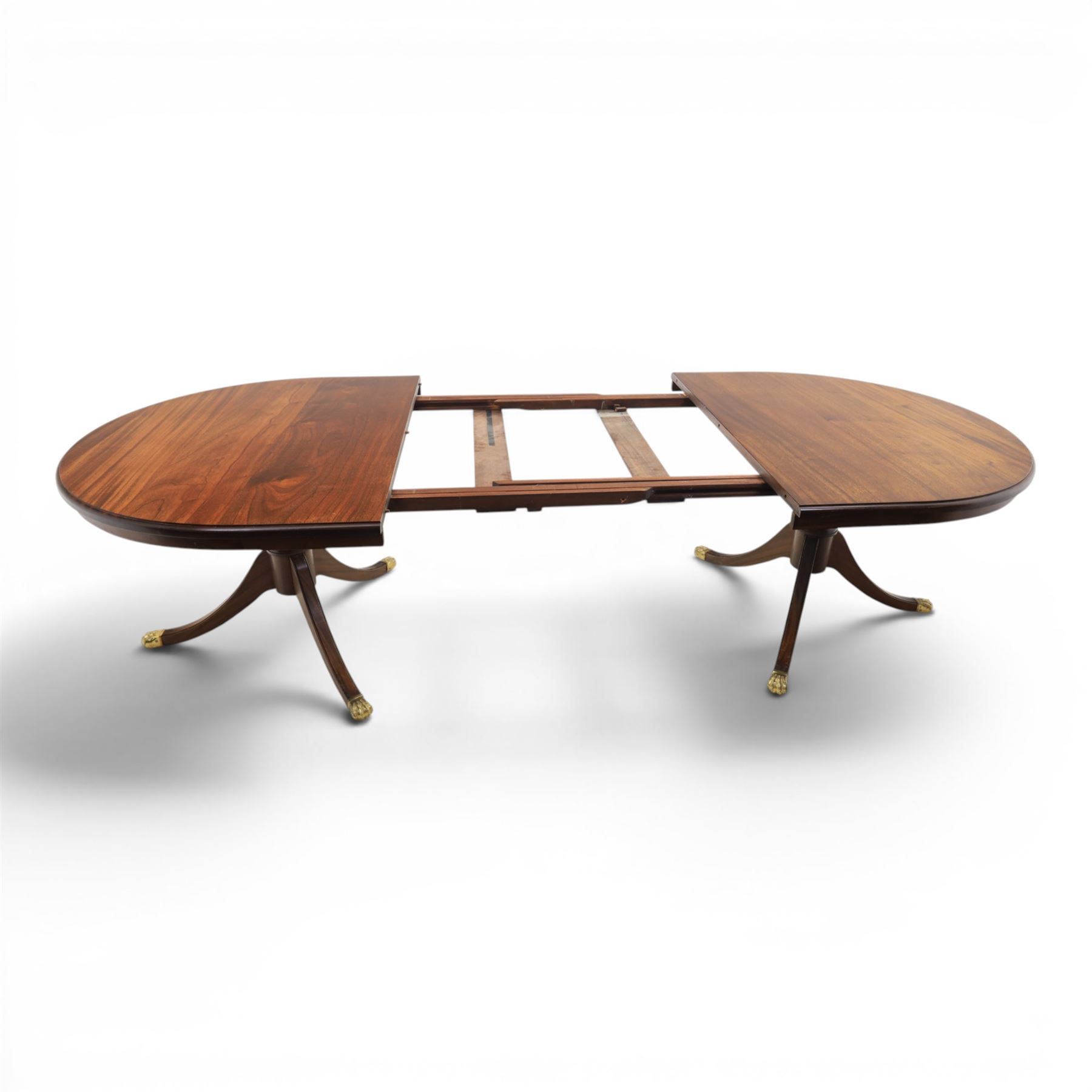 Regency design mahogany extending twin pedestal dining table with two additional leaves, raised on splayed supports terminating brass paw feet
Extends to 268cm