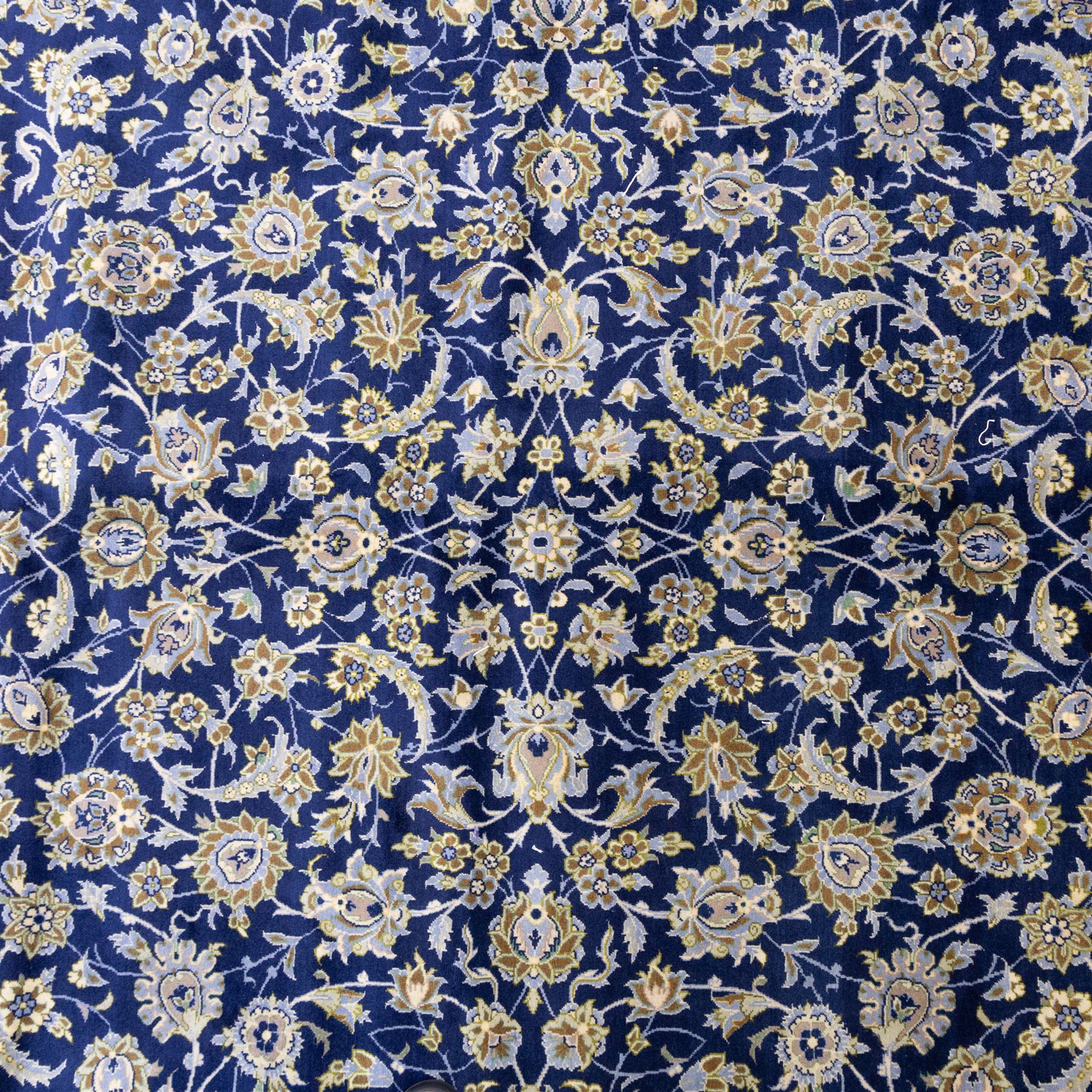 Central Persian Kashan hand-knotted rug, deep blue all-over field, finely decorated with dense scrolling floral sprays, palmettes, and flowering vines in ivory, soft gold, and pale green tones, enclosed by a multi-band floral border with corresponding guard stripes, with cotton fringe ends, signed Shah Abassi Workshop 