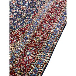 Large Persian Kashan carpet, red and blue ground, the field with central medallion surrounded by interlacing foliate and plant motifs, the border with scrolling design and decorated with flower heads
