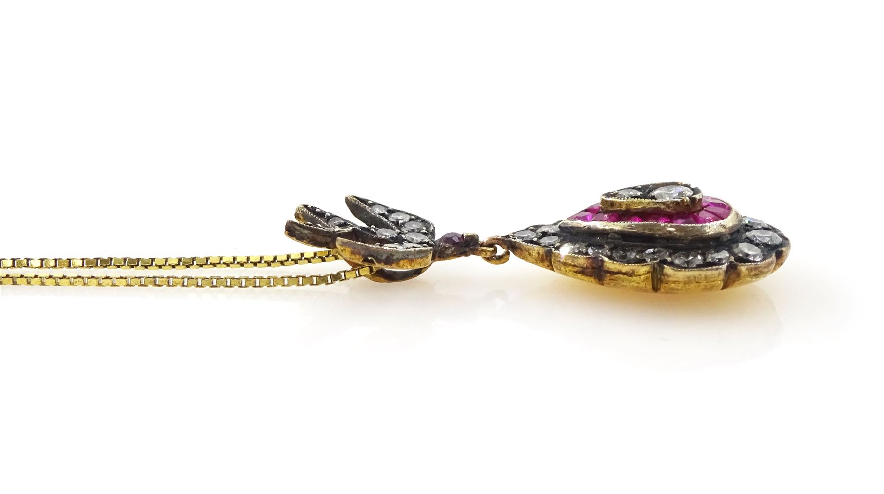 Gold and gold-plated diamond and ruby pendant necklace, the pear shaped pendant, milgrain set with round brilliant cut and single cut diamonds and calibre cut rubies, suspending from a ruby and diamond swallow bail, on a silver-gilt chain, total ruby weight 0.35 carat, total diamond weight 0.60 carat, with World Gemological Institute Report 