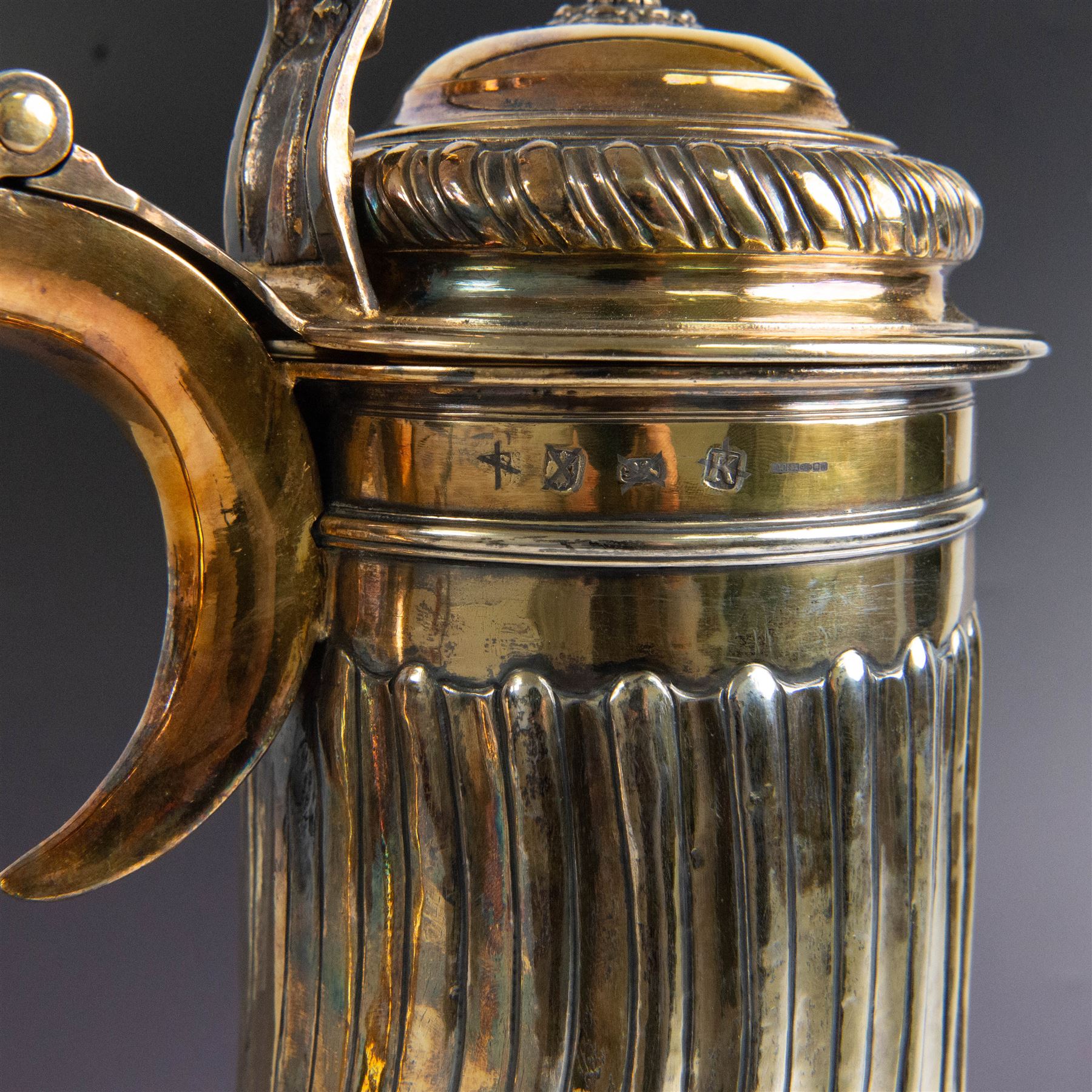 George I silver-gilt wine flagon, of tapering cylindrical form with part fluted body and upon circular spreading foot, with c-scroll handle, domed lid with rose to centre  and scroll thumb piece, hallmarked London 1725, maker's mark indistinct, with later refinements, the original hallmarks struck-through and re-assayed by the London Assay 2021, H33cm