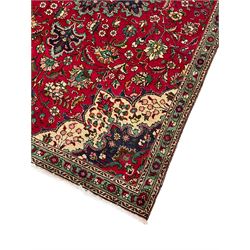 Persian Tabriz red ground rug, all-over interlacing floral design, central medallion decorated with stylised plant motifs, three narrow border bands, the main band decorated with repeating flower head motifs