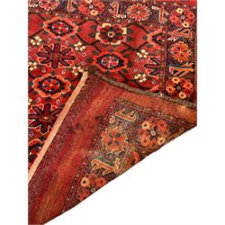 Persian red ground rug, the field decorated with lattice pattern and flowerhead, repeating border decorated with flower heads and leaf motifs