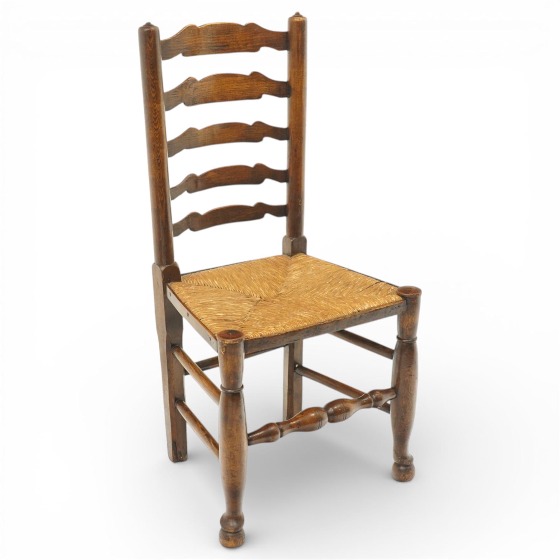 Early 19th century set of six country ladder back chairs, each with five shaped horizontal slats, woven rush seats within square frames, standing on turned forelegs united by peripheral stretchers with turned front rail