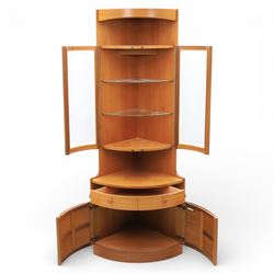 Nathan - 'Squares' corner cabinet, the upper section enclosed by two curved glazed doors with glass shelves, over a shaped base fitted with a single frieze drawer and panelled twin cupboard doors
