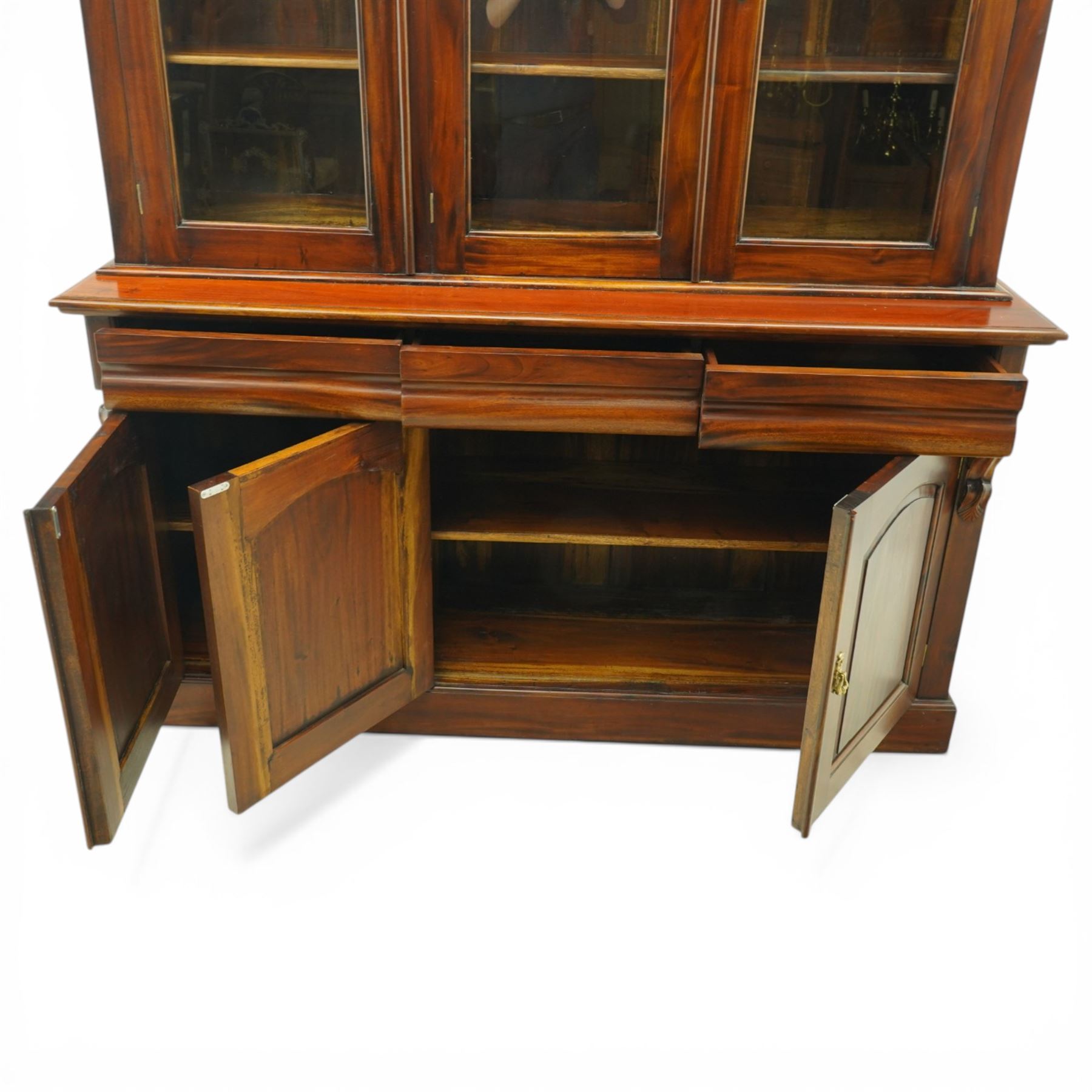 Victorian revival hardwood dresser cabinet, projecting moulded cornice above three glazed doors with shaped tops enclosing shelves, moulded top over three drawers and three panelled cupboard doors, flanked by applied carved brackets, on plinth base