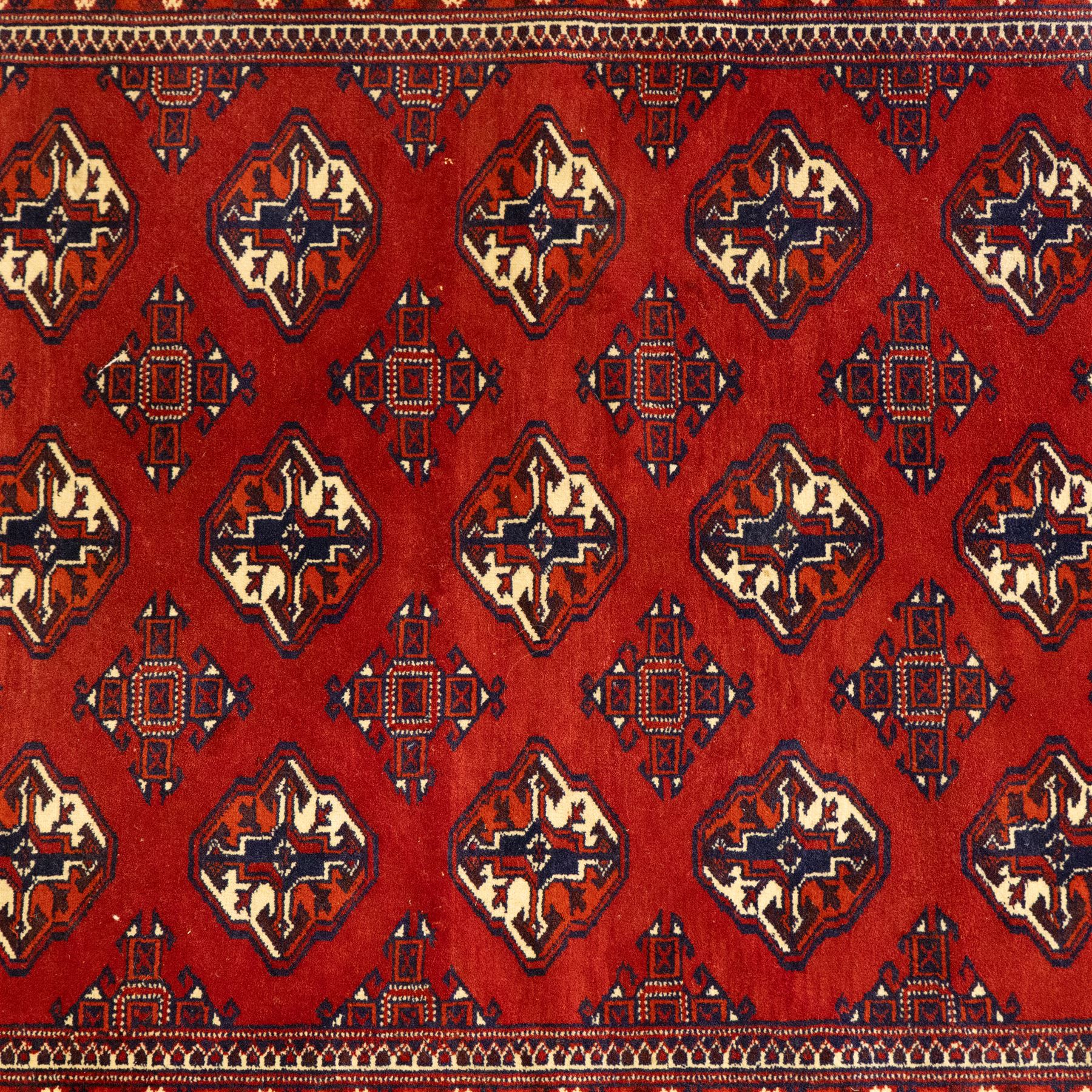 Three rugs,  comprising a Baluch rug in crimson ground, 179x97cm, a Tekke Bokhara rug in crimson ground, 201x132cm, and a Bokhara rug in ochre ground, 125x175cm 