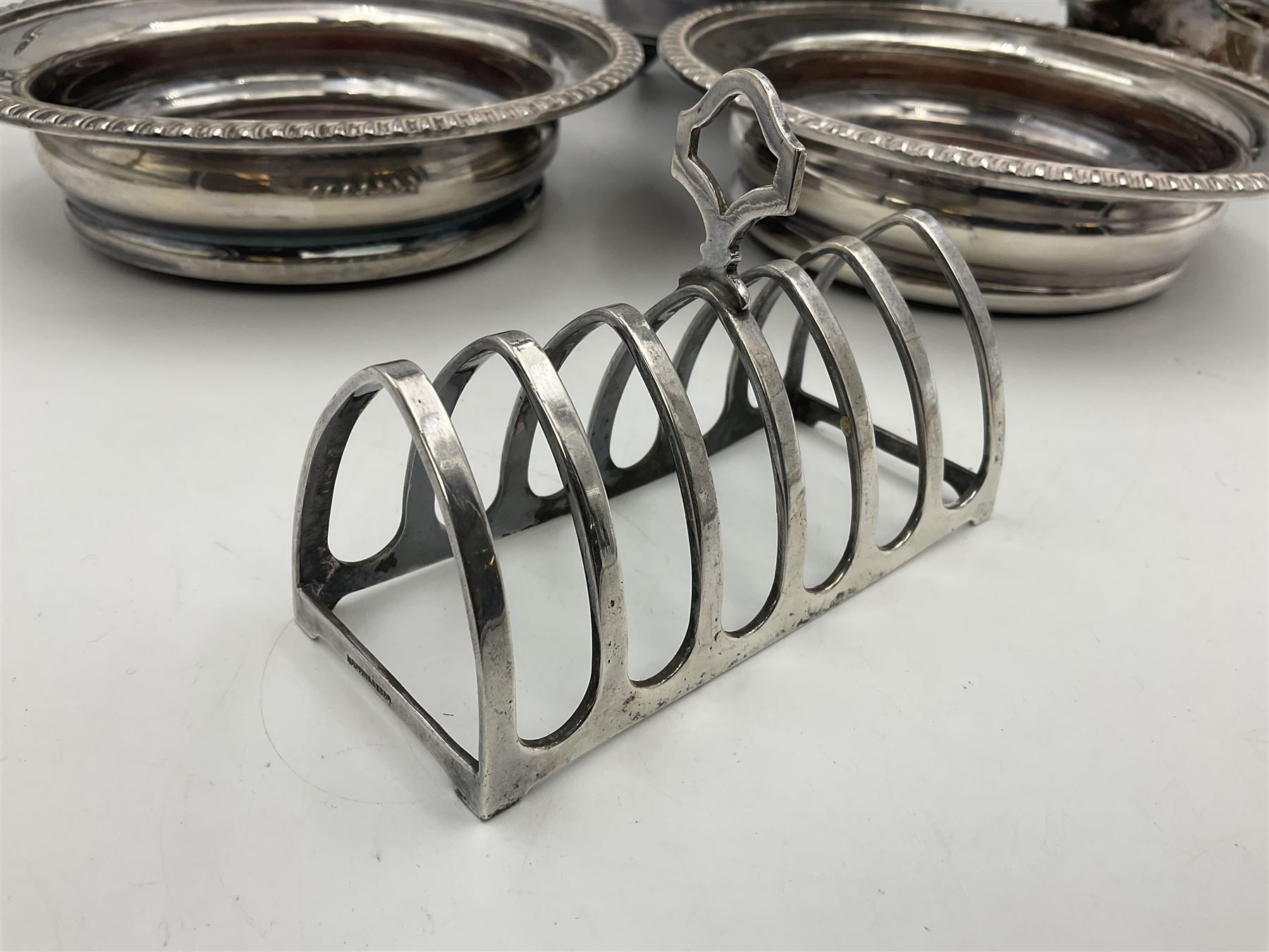 Silver plated seven bar toast rack by Mappin & Webb, together with other silver plated items including pair of bottle coasters, swing handled baskets and two sauce boats