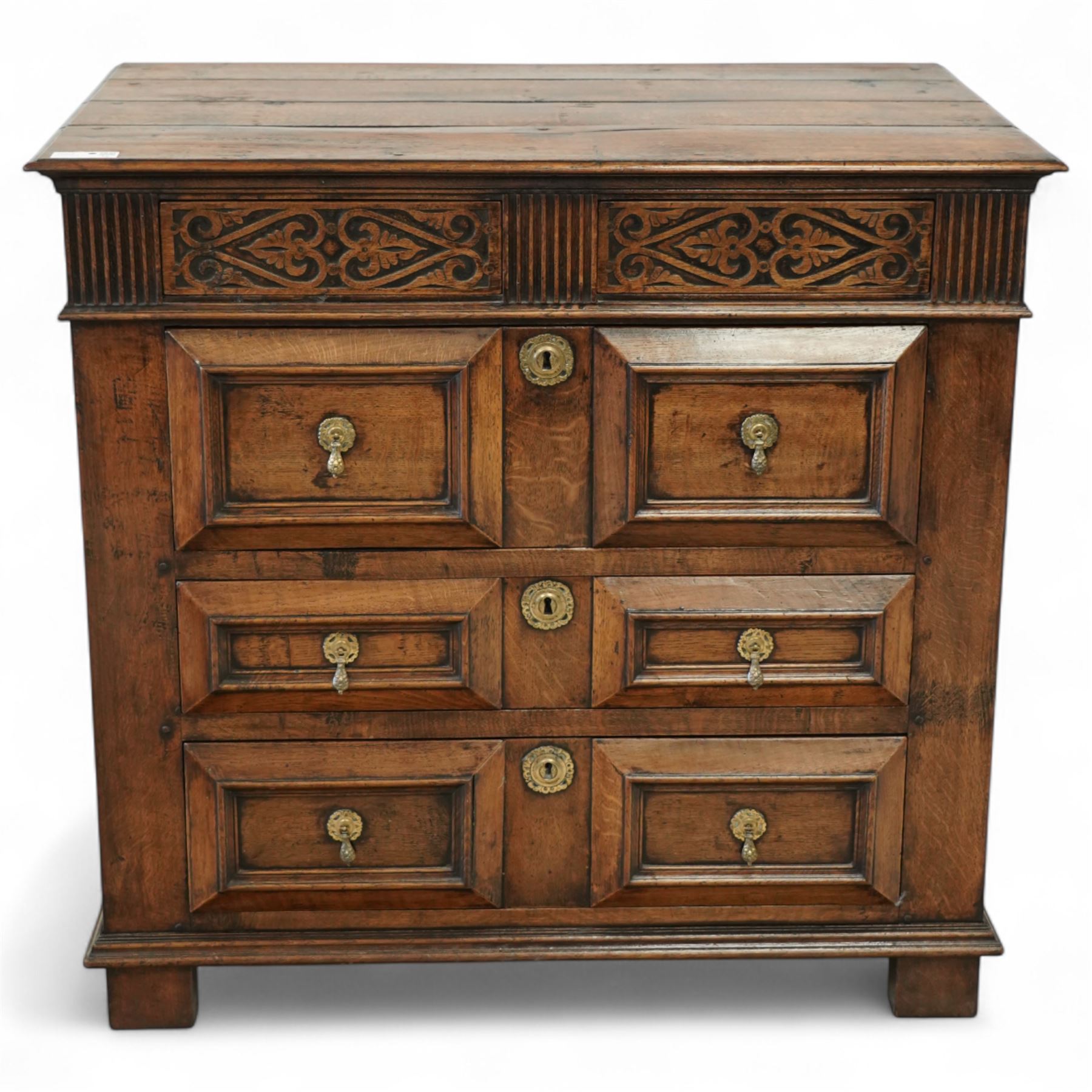 John Nethercott & Co - late 20th century hand-made oak 17th-century design chest of drawers, rectangular pegged and planked top above scrollwork carved frieze concealing two drawers, over three drawers, all with raised rectangular moulding and drop handles, raised on stile feet, the back with dated label for John Nethercott & Co