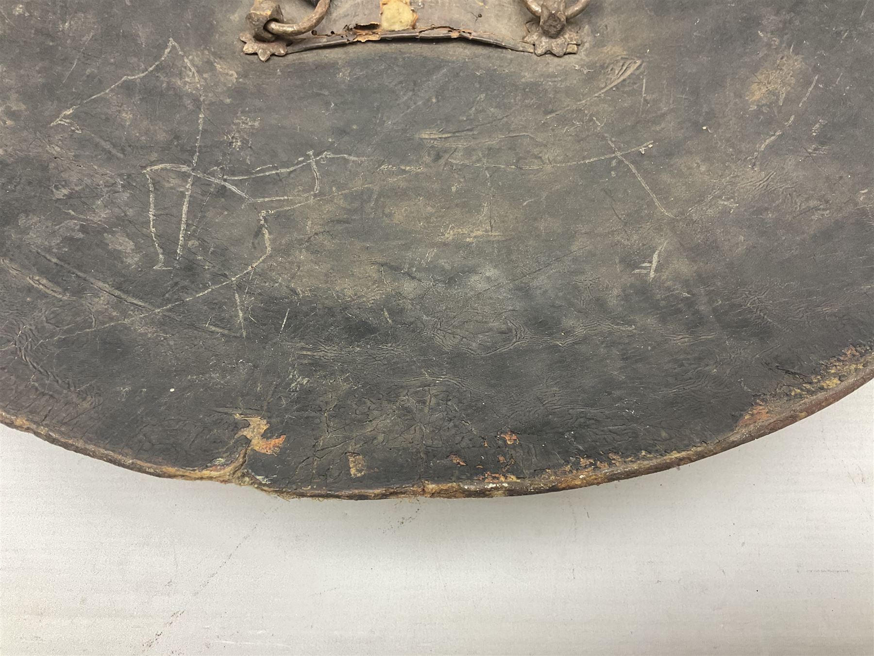 Indian black lacquered hide shield/dhal, of circular convex form fitted at its centre with four pierced iron bosses, each of hemispherical form with wide brims, the bosses corresponding on the inside with four iron rings for enarmes D53.5cm