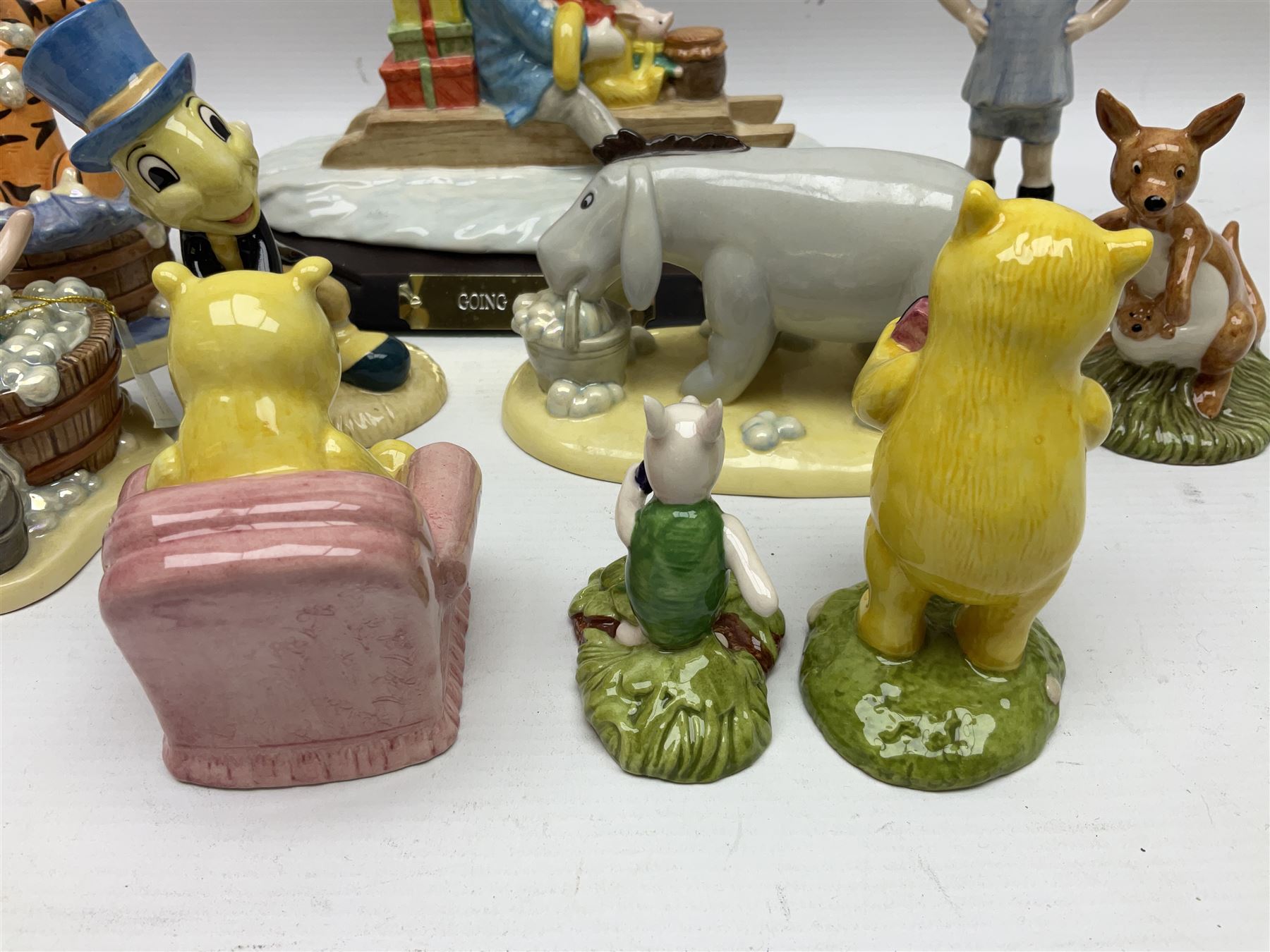 Nine Royal Doulton Winnie the Pooh Collection figures, including Oh Dear Bath Time's Here, Going Sledging, Tigger's Splash Time and Christopher Robin, together with a Royal Doulton Disney Showcase Jiminy Cricket figure, all boxed