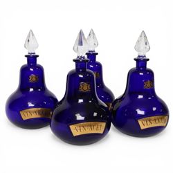 Set of four 20th century Royal Pharmaceutical Society blue glass bottles, of bellied form with clear cut glass spire stopper, each body bearing gilt label in Latin: VIN:ACET:, VIN:ANTIM:, VIN:XERIC:, and VIN:FERR:, and gilt Royal Pharmaceutical Society crest to neck, H25cm

Provenance: From the collection of the family of Peter Green, a practising pharmacist whose career spanned the mid to late 20th century. During his professional life he managed pharmacies in Yeovil, Somerset, and later Selles Chemist in Filey, North Yorkshire, before purchasing and running his own business, Peter Green Pharmacy, located in the Market Place, Malton. The bottles were displayed as part of the traditional shop fittings in both the Filey and Malton pharmacies and were retained as part of his collection.