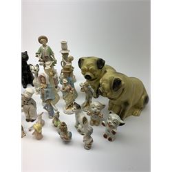 A collection of various ceramic figurines, to include pair of small 19th century Staffordshire cats, Royal Doulton cat, Coalport cat, pair of 19th century pug dogs, two fairings inscribed Good Templars, two Bonzo dog peppers, a number of pin cushion dolls, various 20th century and later black pottery cats, Victorian bisque figures, etc. 