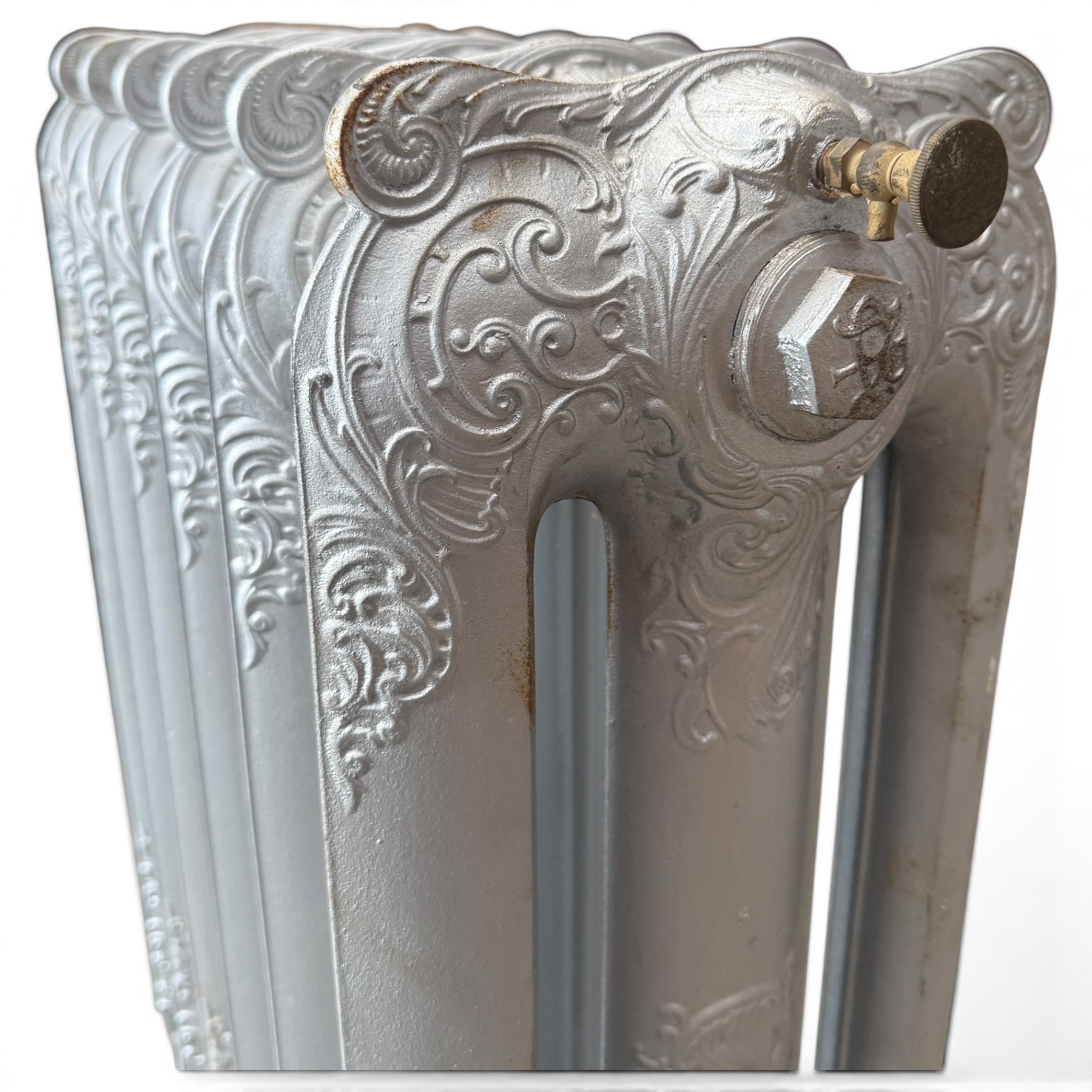 French ornate cast iron column radiator of Rococo Revival design, each section cast with scrolling foliate decoration with rocaille and cartouche motifs, with brass valve and integral bracket feet, in painted silvered finish
