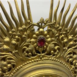 20th century gilt metal monstrance, in the Gothic revival style, with glazed aperture to centre surrounded with clear paste stones, in a pierced floral and scroll border set with coloured paste stones, within a sunburst surround, on a paste set knopped stem and similar foliate foot, H59.3cm